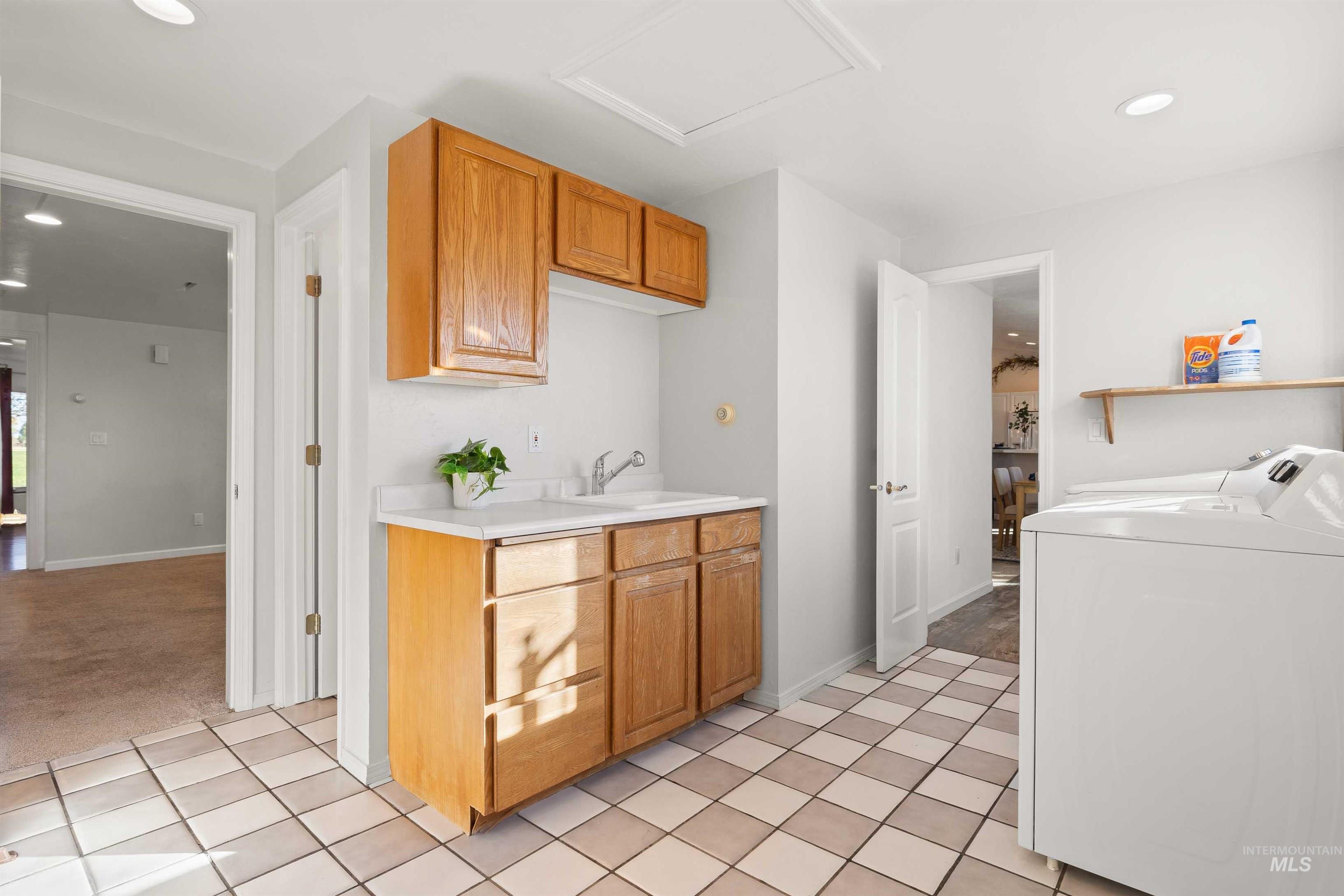 Kitchen featuring recessed lighting, light countertops, light tile patterned flooring, brown cabinetry, and light colored carpet
