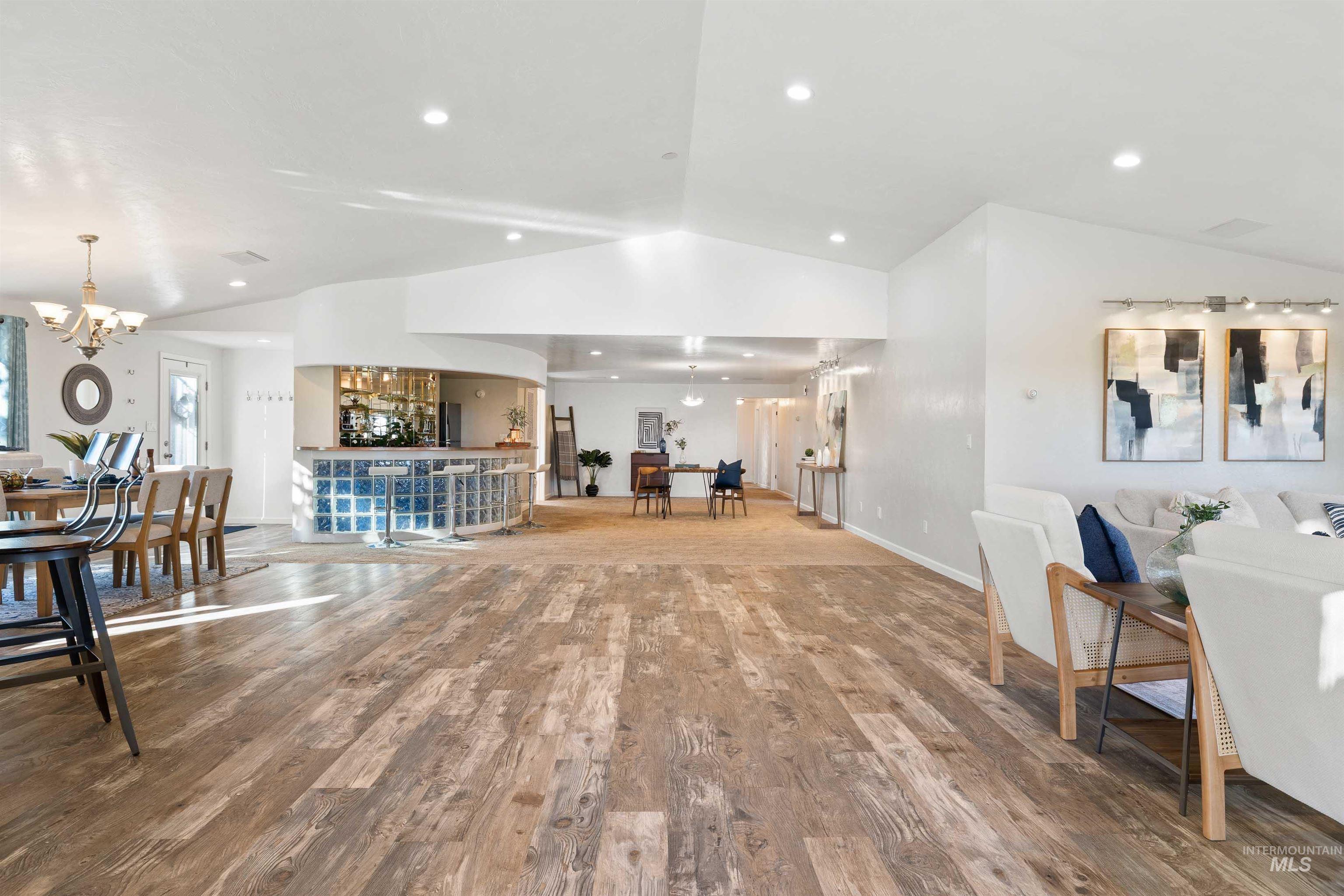 Living room featuring lofted ceiling, wood finished floors, a chandelier, and recessed lighting