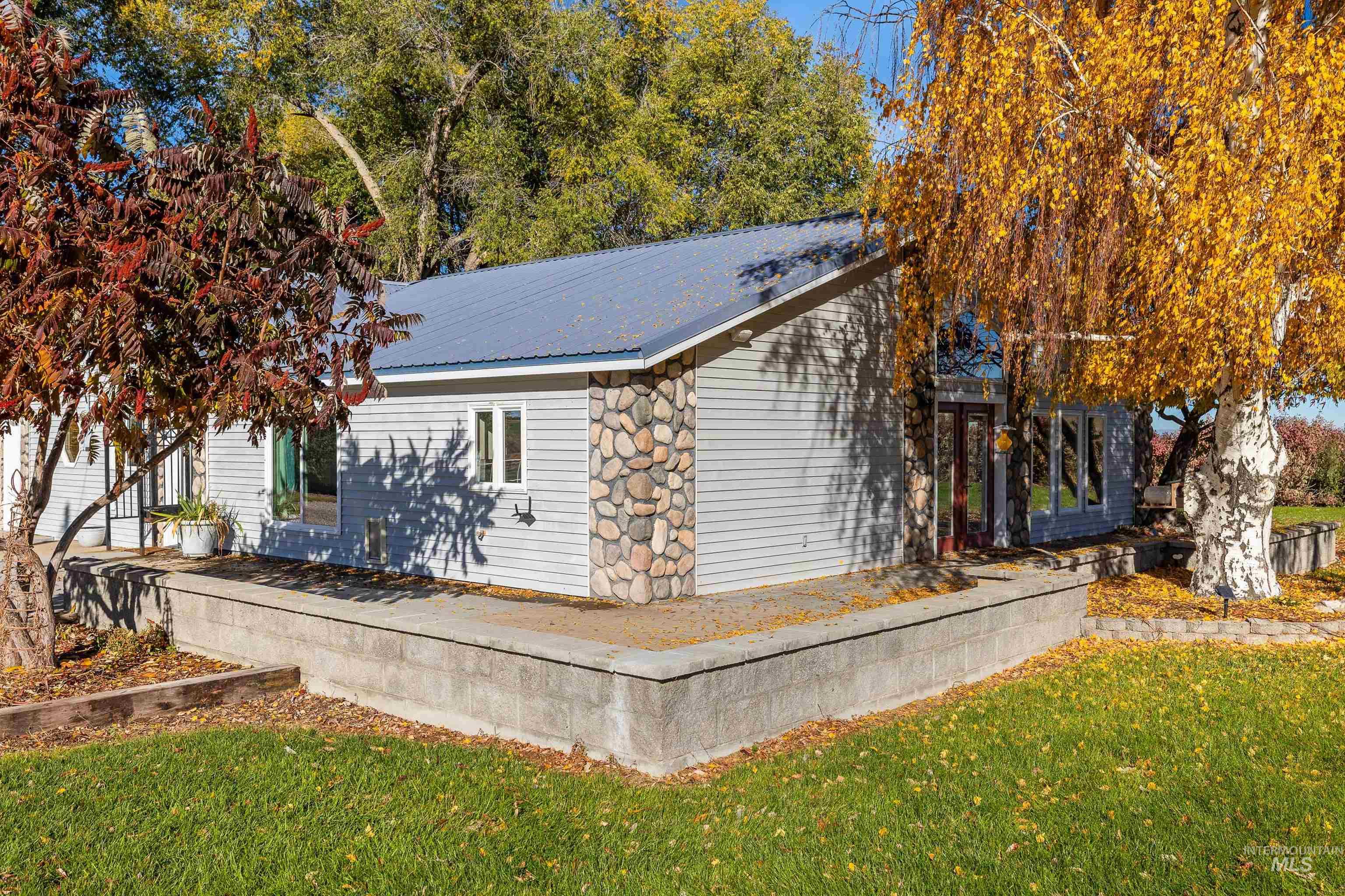 View of side of home with a yard, a metal roof, and stone siding