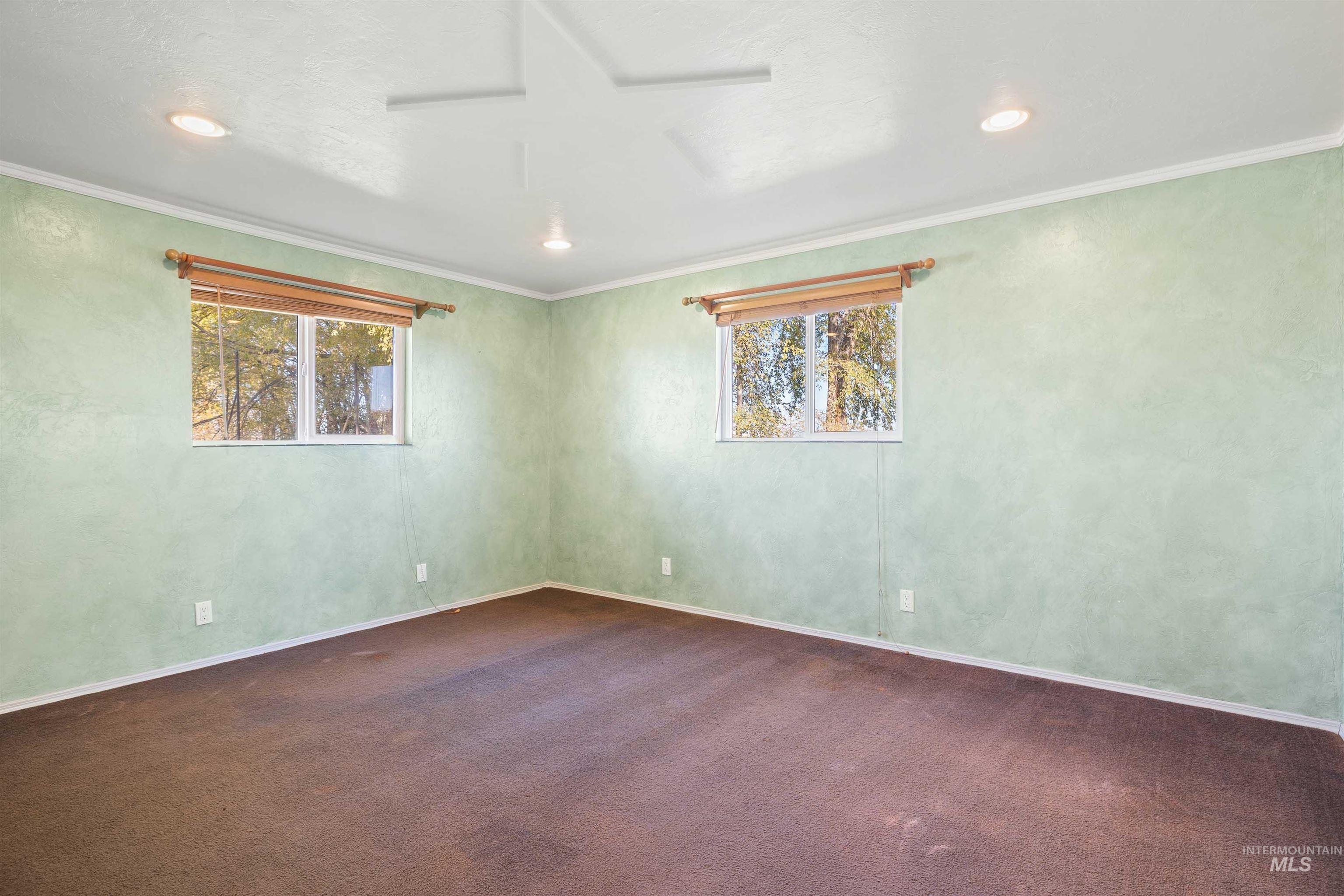 Empty room with ornamental molding, dark colored carpet, and recessed lighting