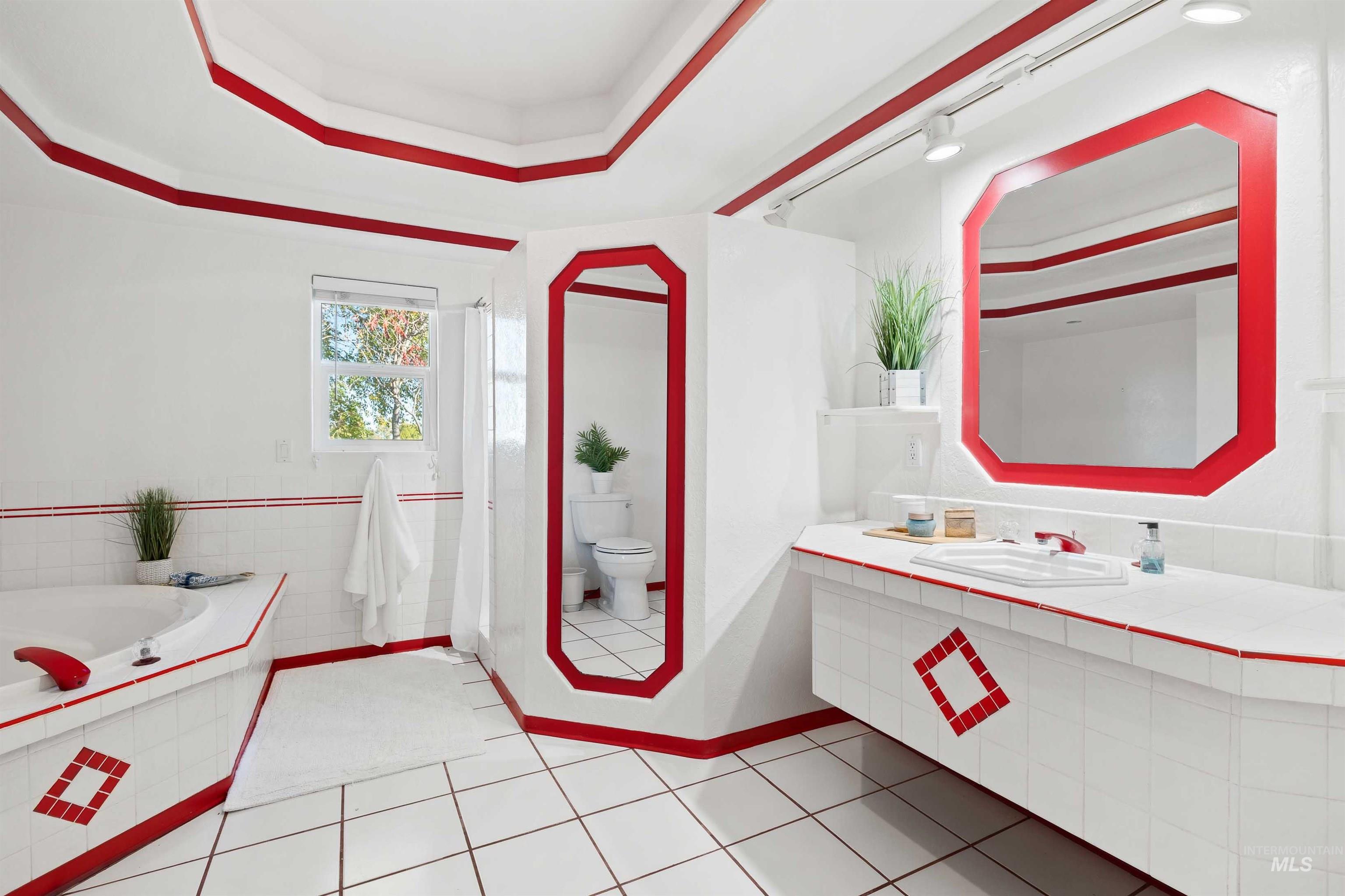 Bathroom featuring a raised ceiling, a garden tub, vanity, and light tile patterned flooring