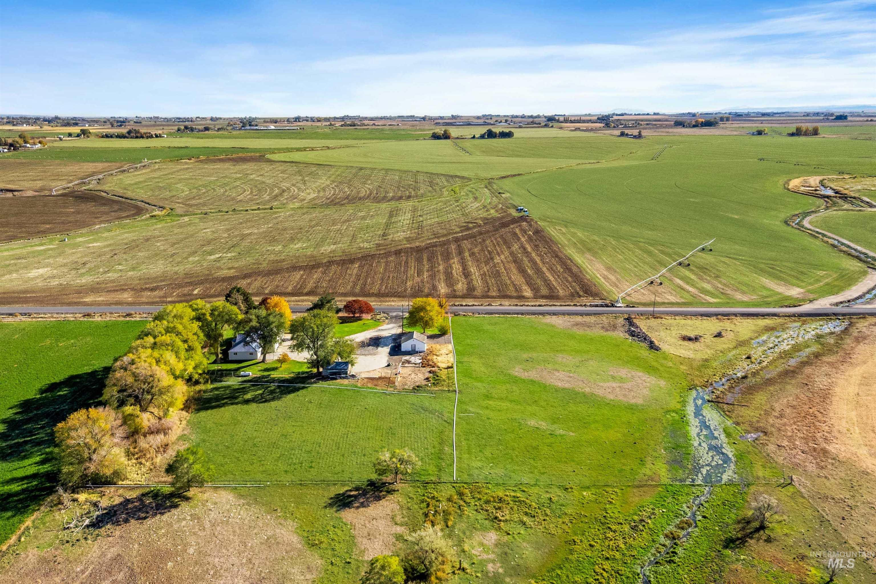 Aerial view of property and surrounding area featuring rural landscape and large plots for crops