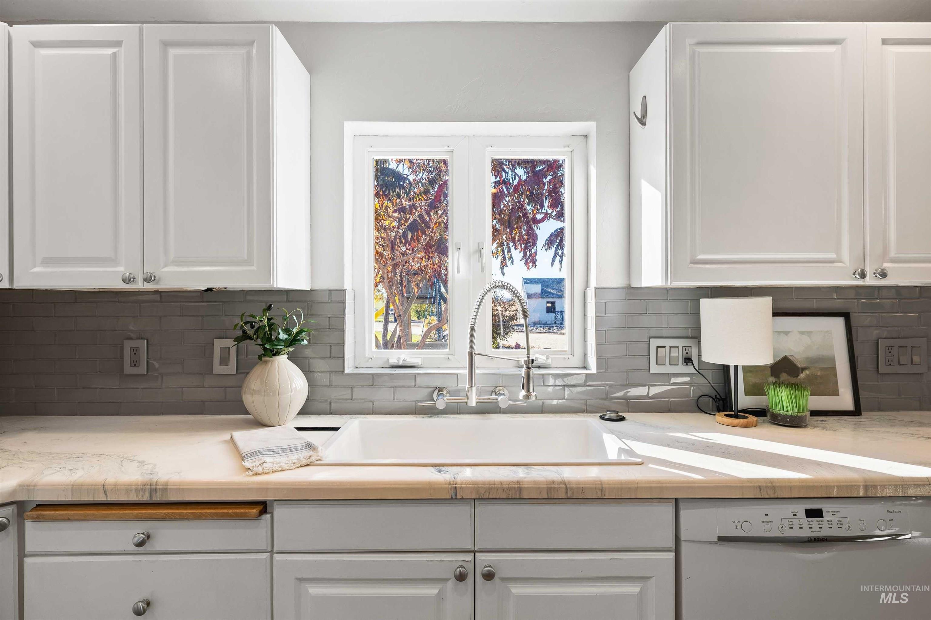 Kitchen featuring white cabinets, dishwasher, and decorative backsplash