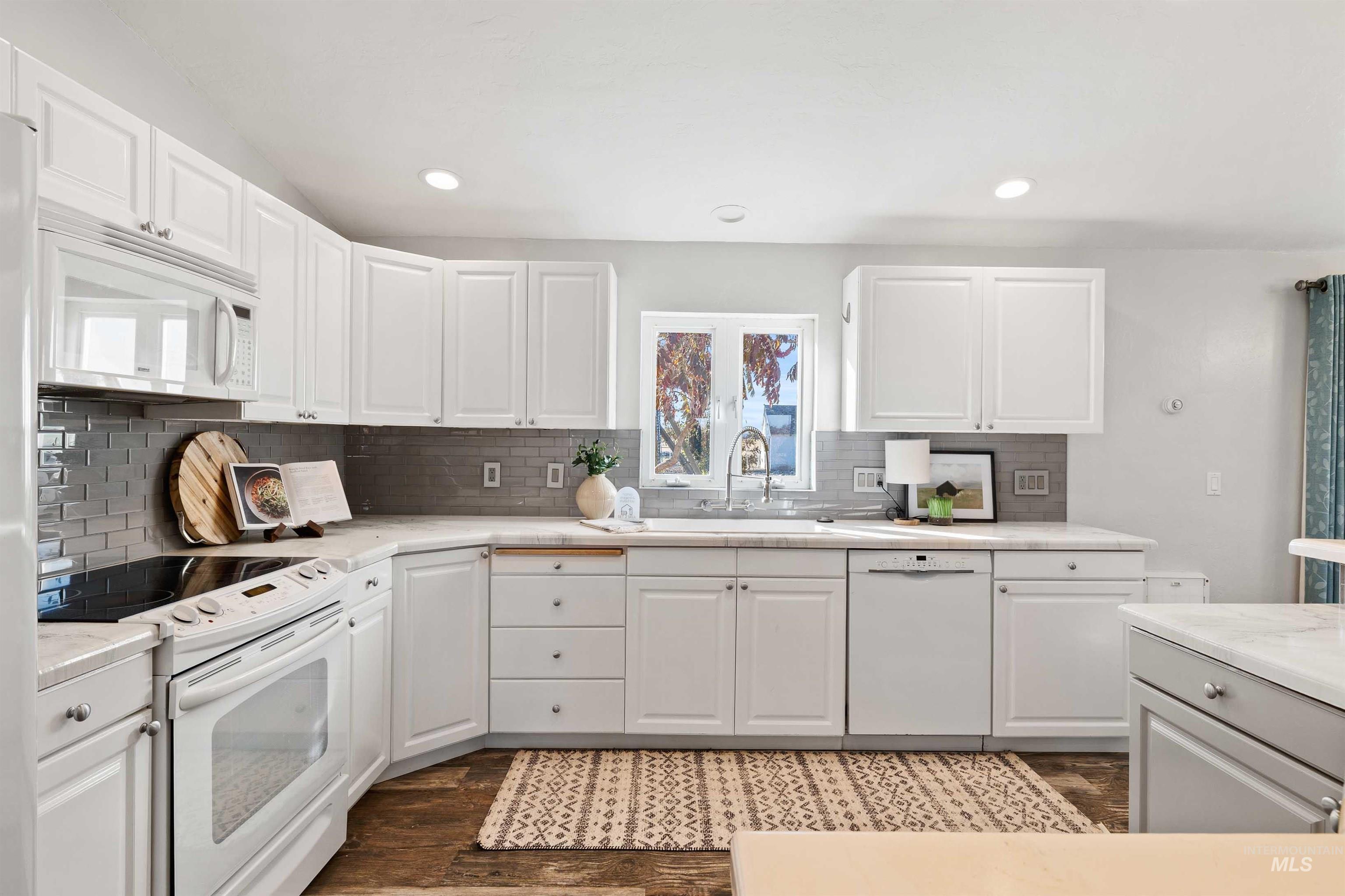 Kitchen featuring white appliances, white cabinets, decorative backsplash, and recessed lighting