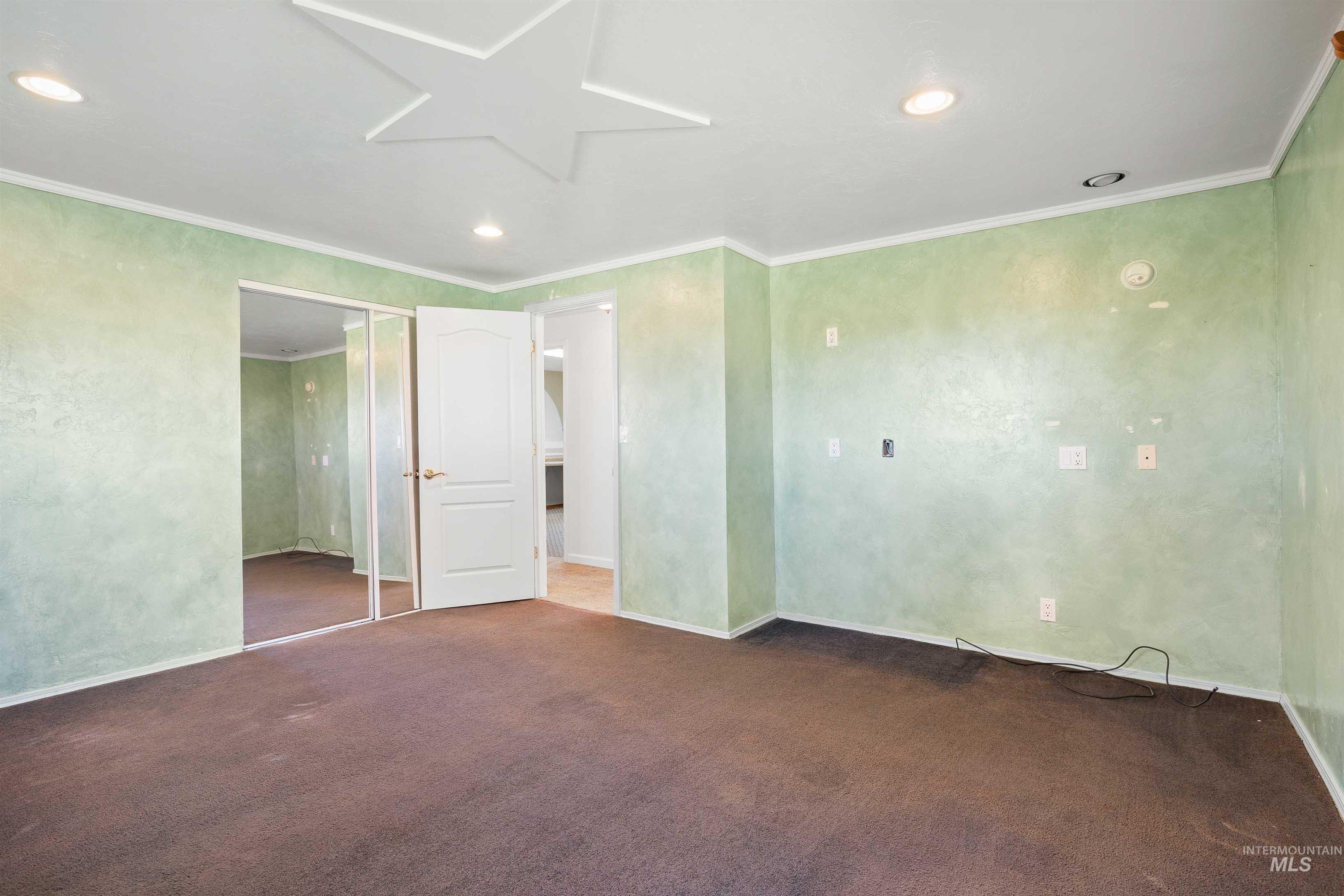 Unfurnished bedroom with ornamental molding, recessed lighting, dark colored carpet, and a closet