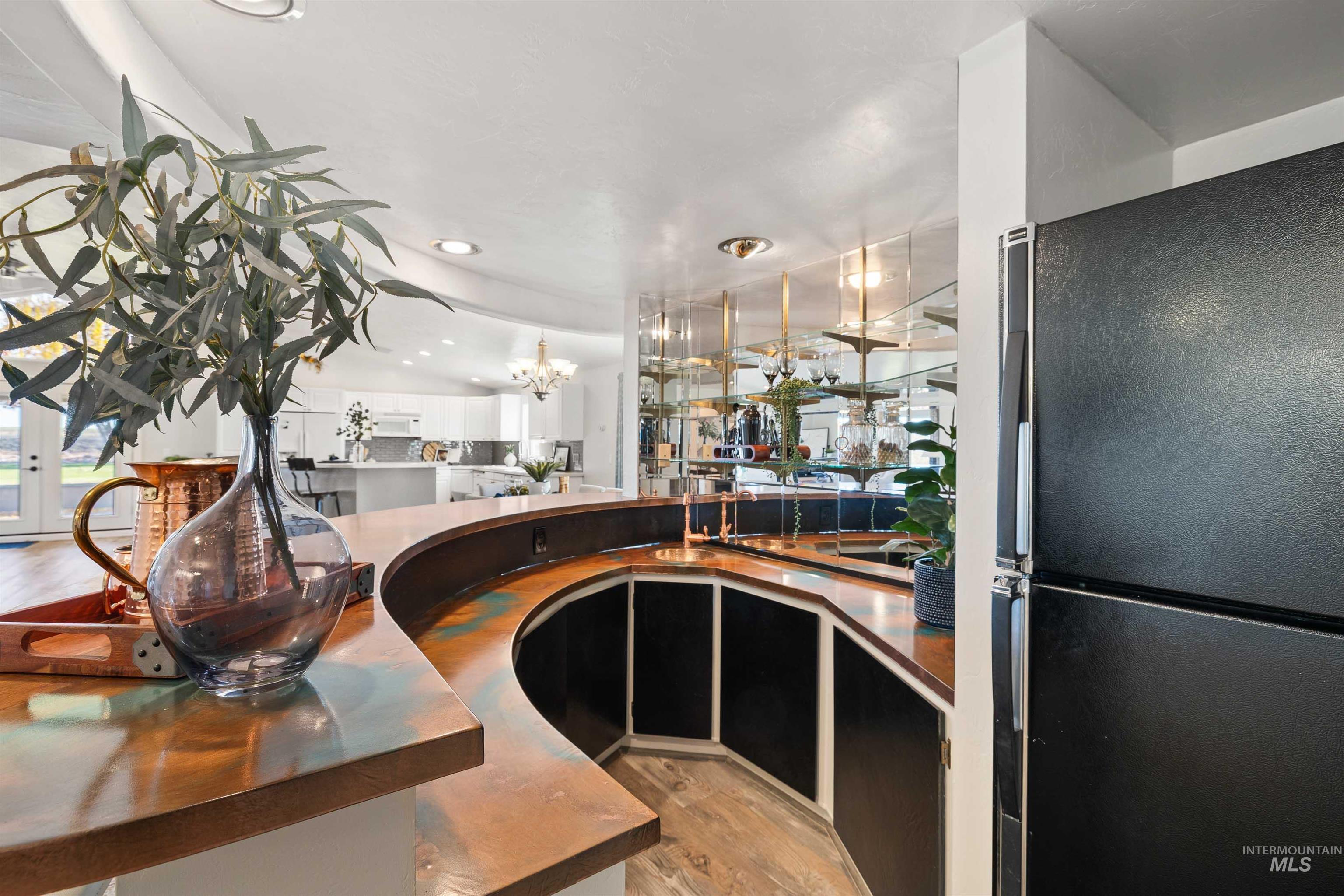 Bar area featuring freestanding refrigerator, light wood finished floors, a chandelier, recessed lighting, and decorative backsplash