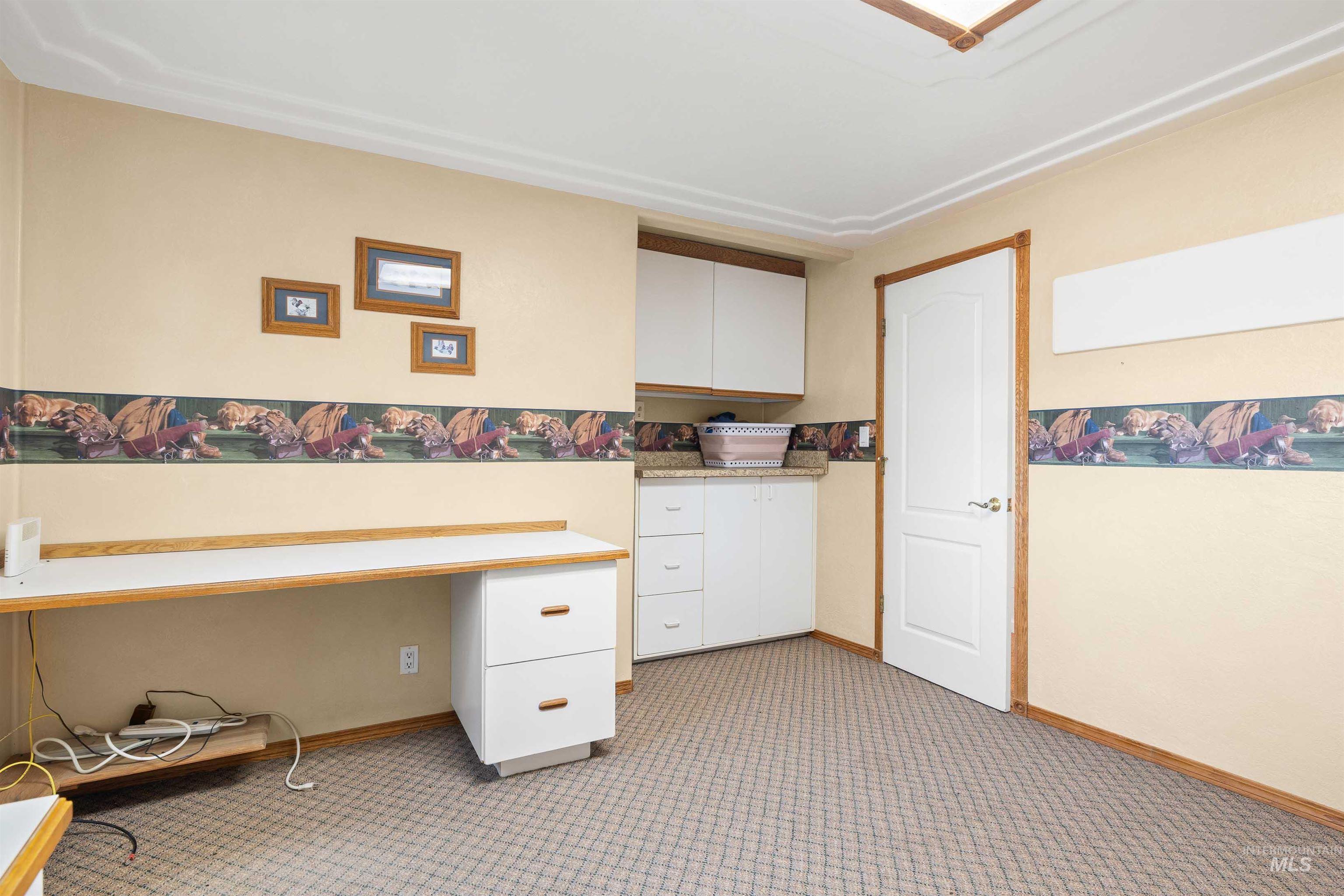 Unfurnished office with built in desk and light carpet