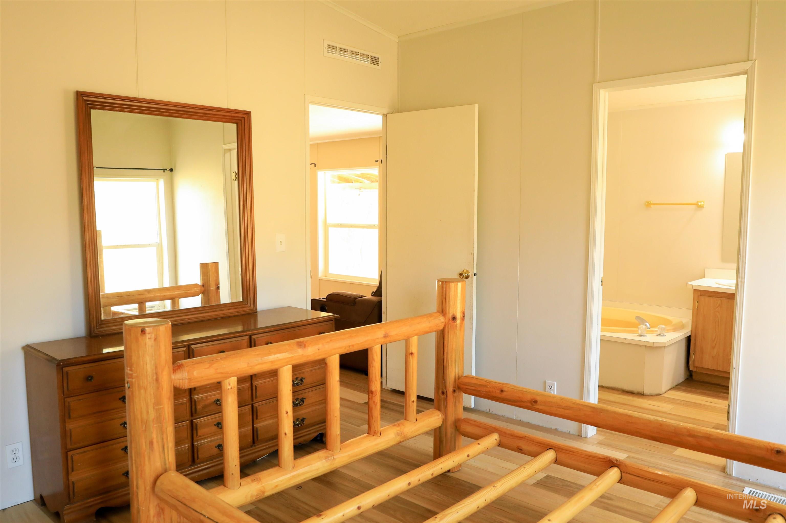 Bedroom with light wood-style floors and connected bathroom