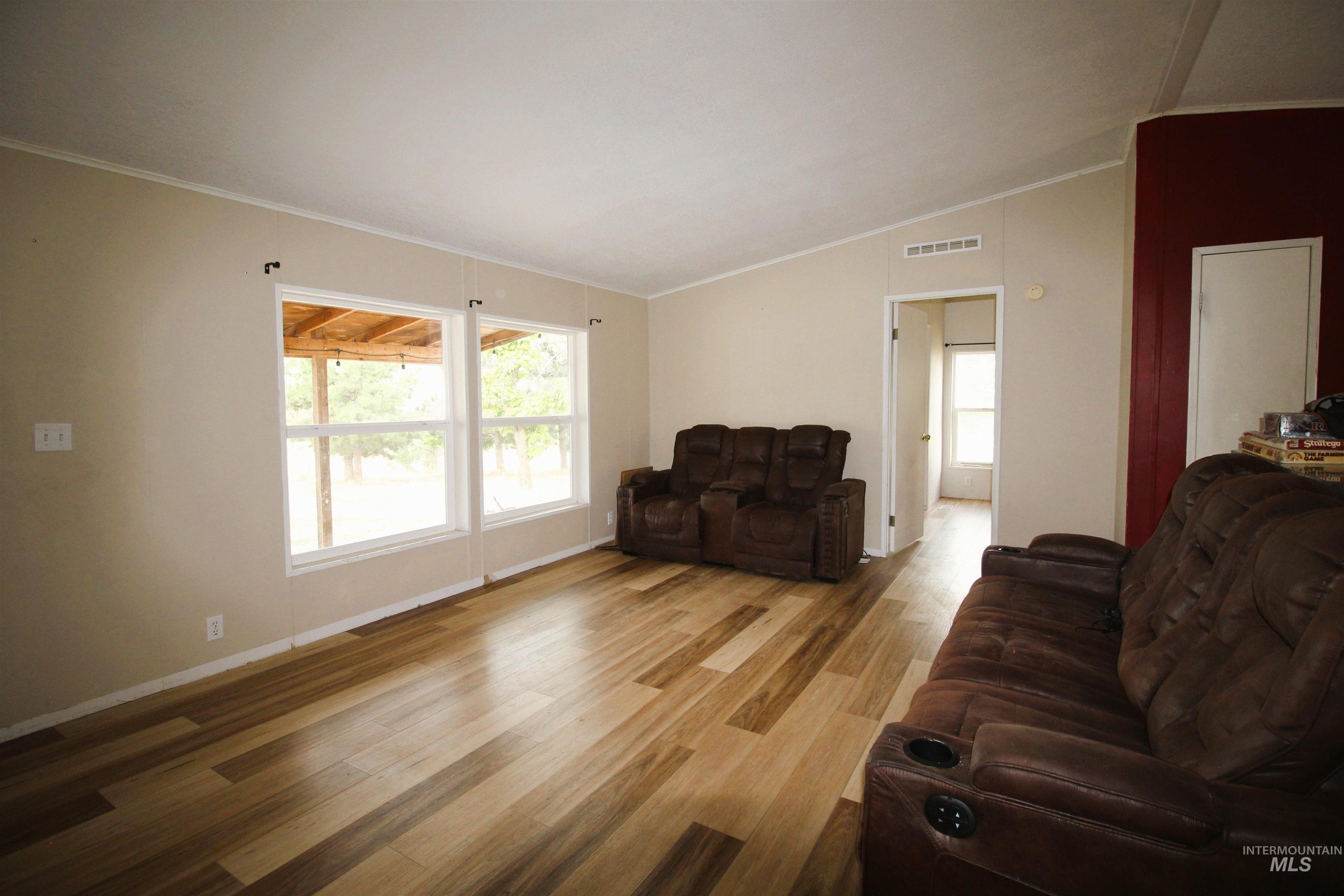 Living area with crown molding, light wood finished floors, and vaulted ceiling