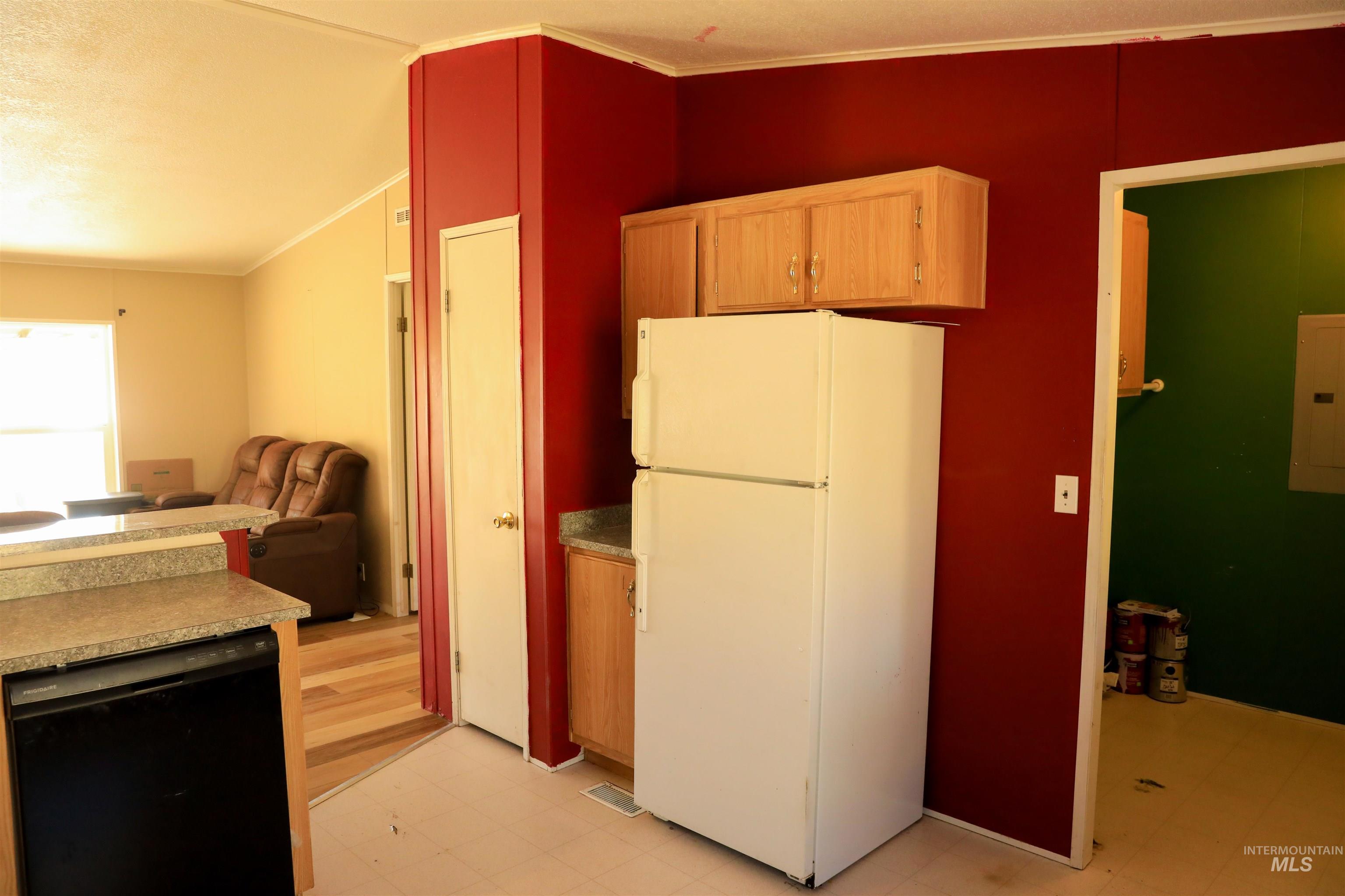 Kitchen with freestanding refrigerator, ornamental molding, black dishwasher, open floor plan, and light countertops