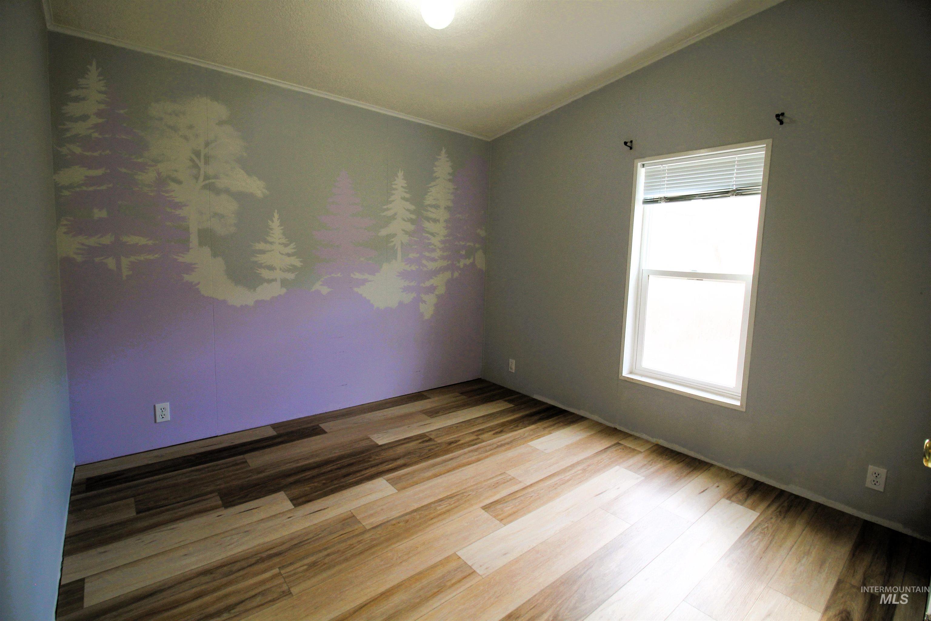 Empty room featuring light wood finished floors and vaulted ceiling