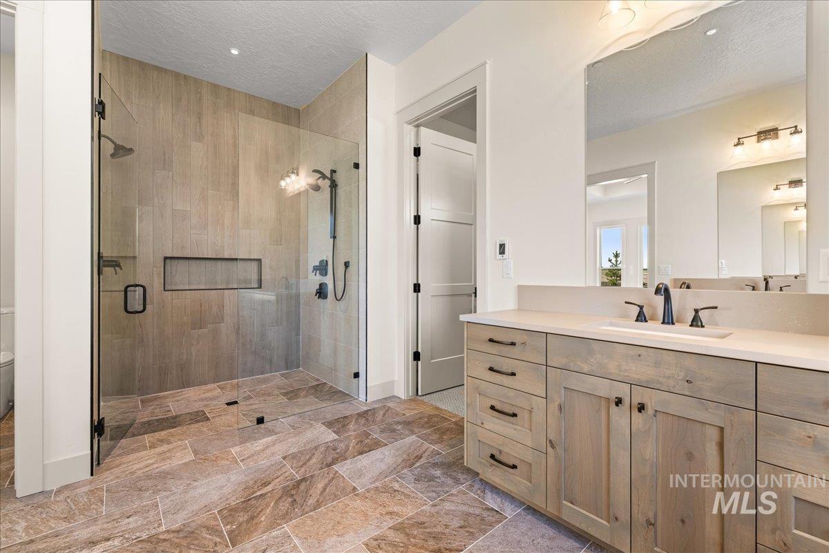 Bathroom featuring vanity, a stall shower, and a textured ceiling