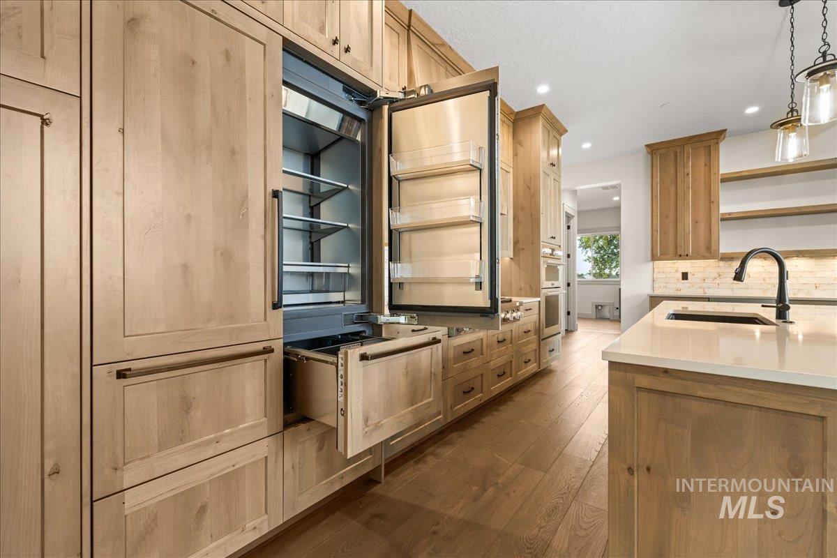Kitchen featuring open shelves, dark wood-style flooring, pendant lighting, light stone counters, and backsplash