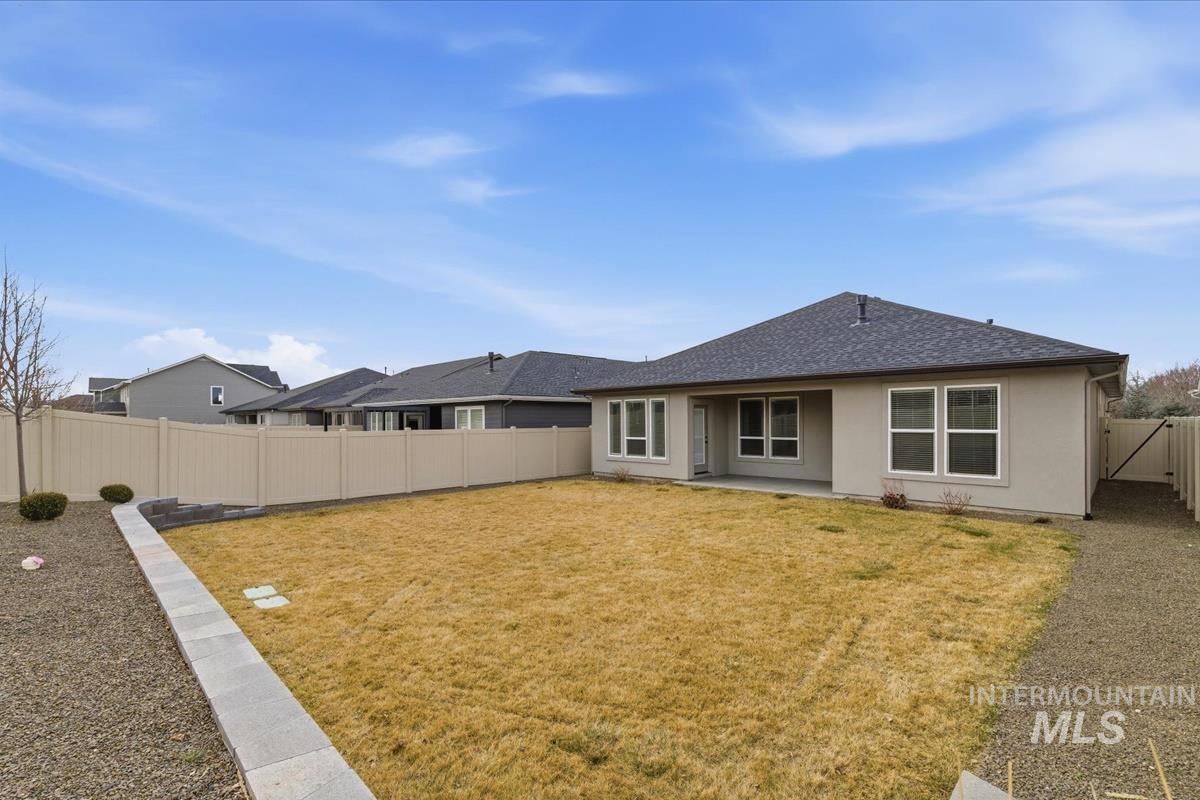 Back of house featuring a fenced backyard, a patio area, and roof with shingles
