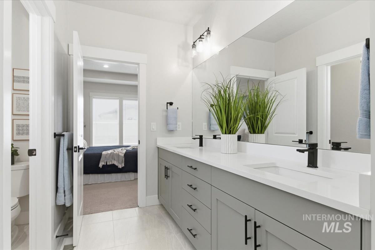 Ensuite bathroom featuring double vanity and light tile patterned flooring
