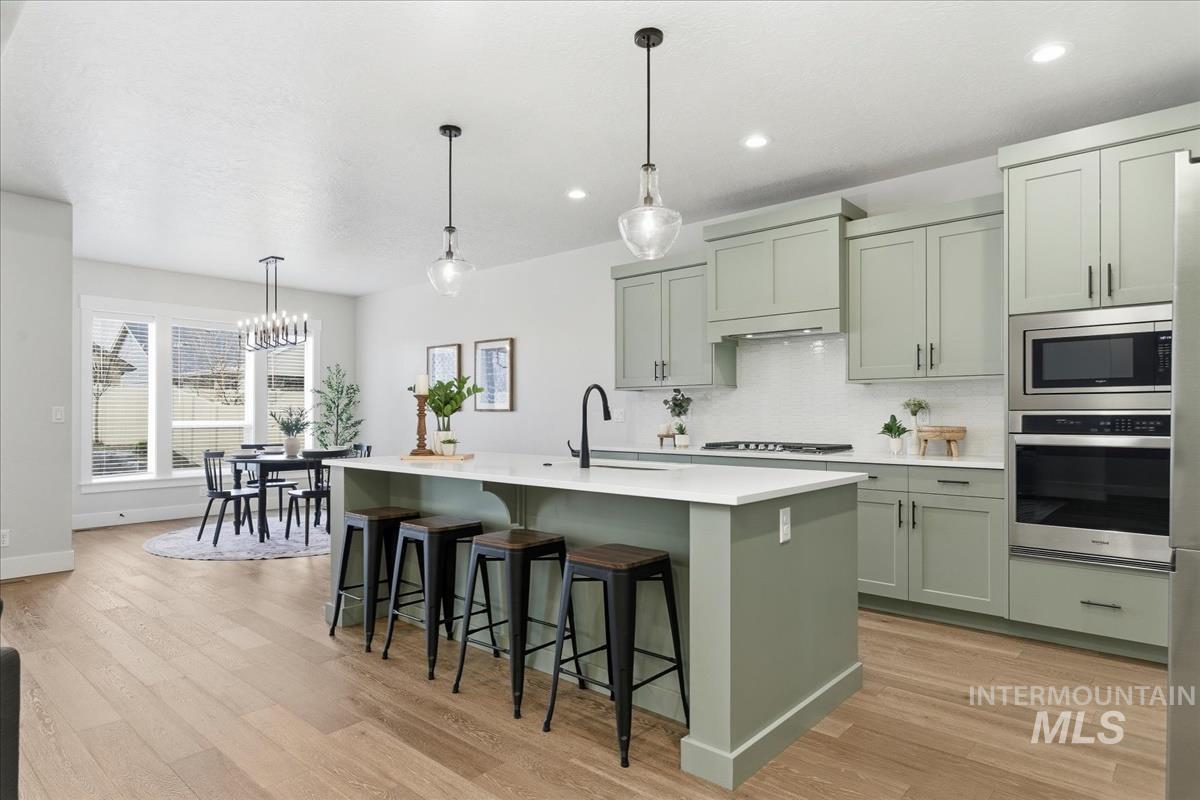 Kitchen featuring hanging light fixtures, stainless steel appliances, a breakfast bar area, and decorative backsplash