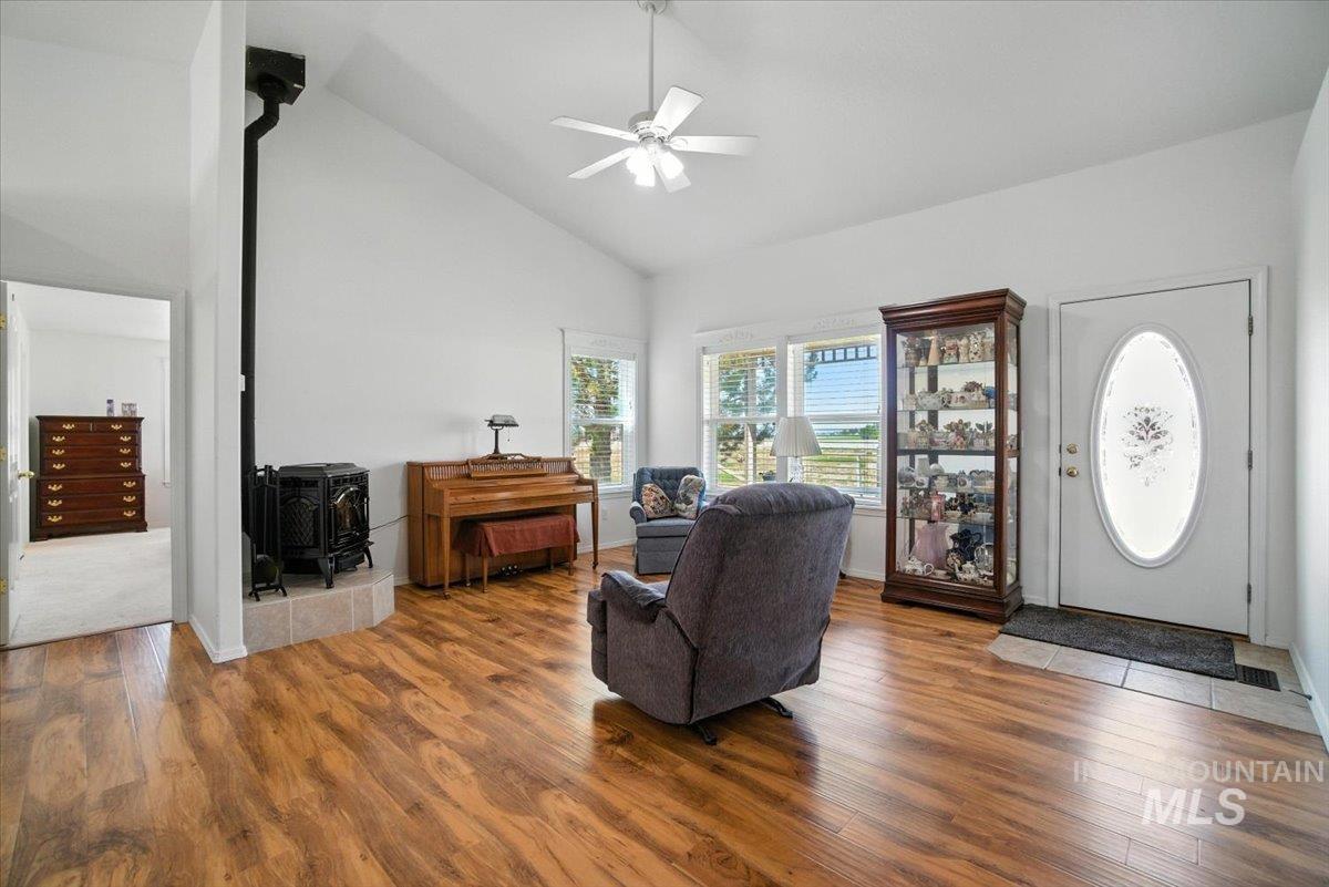 Entryway with a wood stove, wood finished floors, a ceiling fan, and high vaulted ceiling