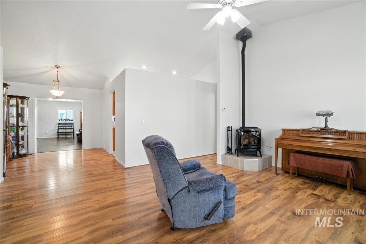 Living area featuring a wood stove, wood finished floors, a ceiling fan, recessed lighting, and lofted ceiling