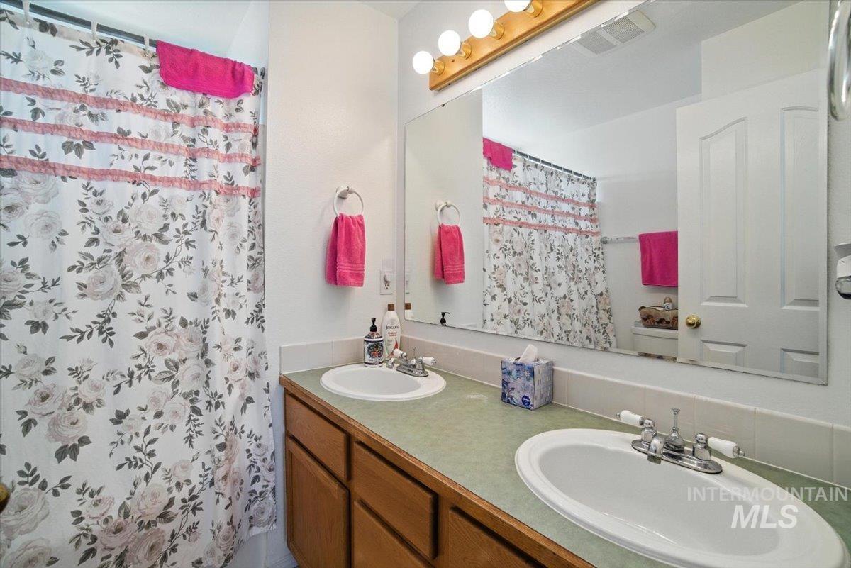 Bathroom with double vanity and a shower with curtain