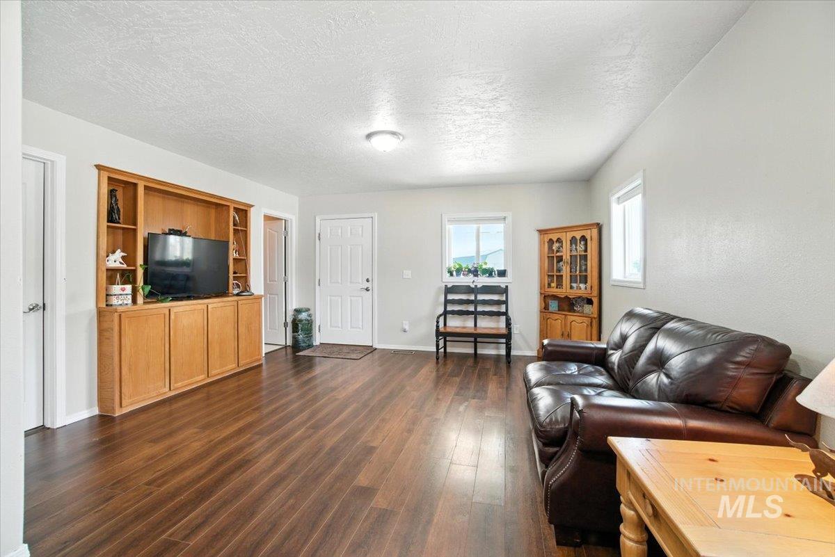 Living room featuring dark wood-style flooring and a textured ceiling