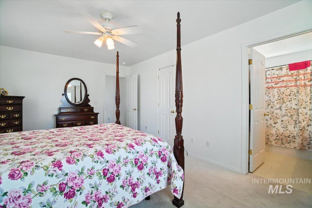 Bedroom featuring light carpet, ensuite bath, and a ceiling fan