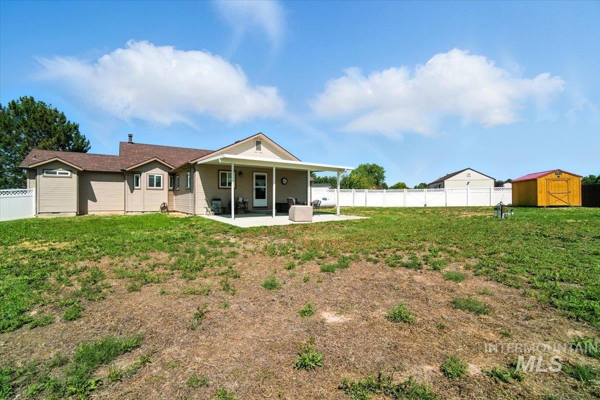 Back of house featuring a patio, a storage unit, and a fenced backyard