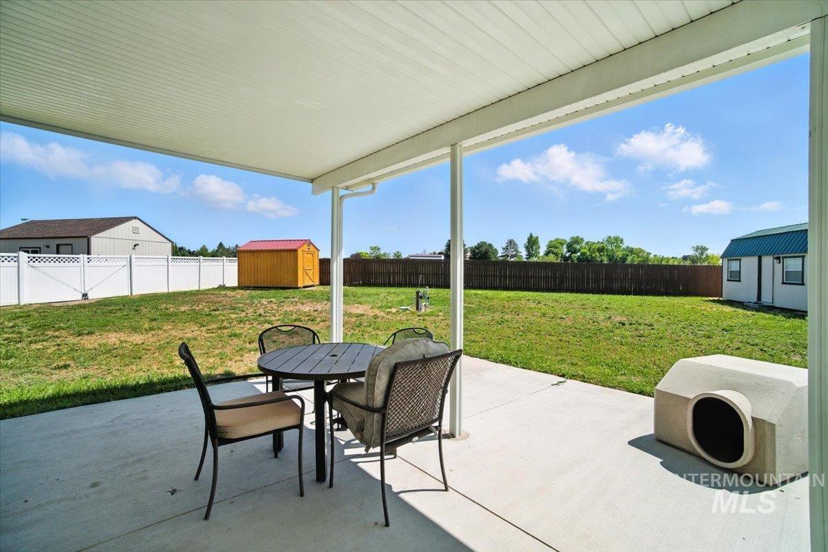 Fenced backyard with a shed, outdoor dining space, and a patio