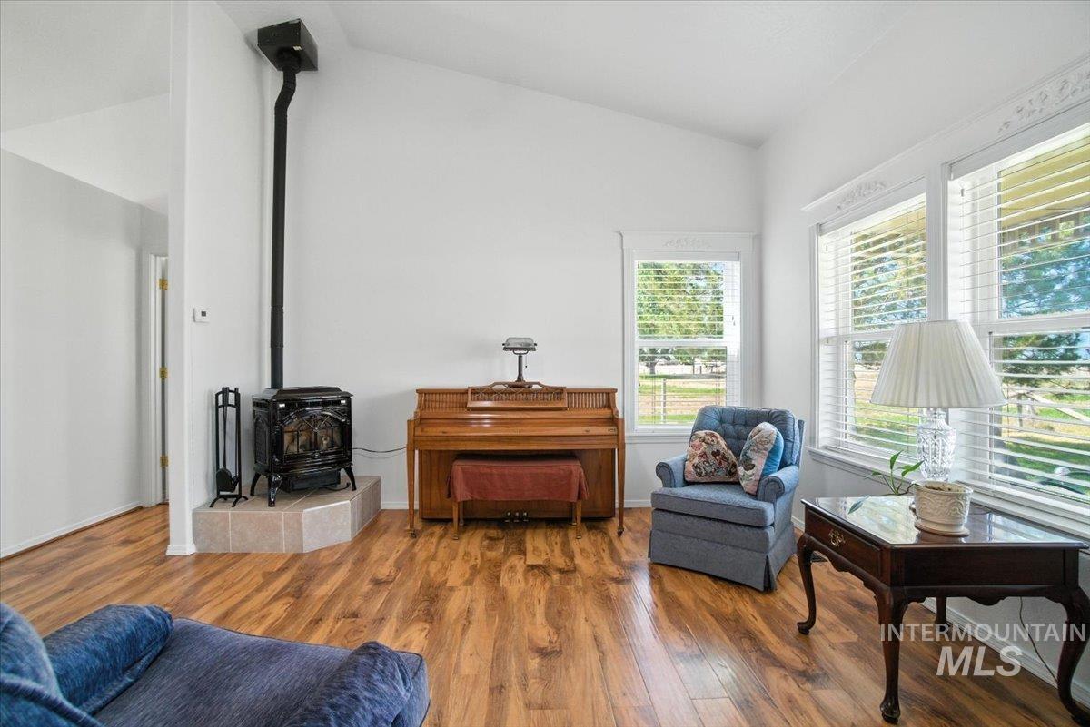 Living area with vaulted ceiling, a wood stove, and wood finished floors