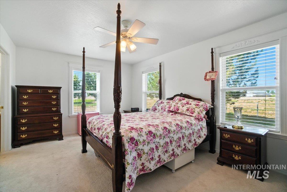 Bedroom with light colored carpet and a ceiling fan