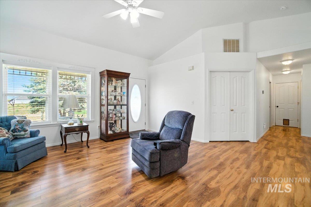 Living area featuring ceiling fan, wood finished floors, and high vaulted ceiling