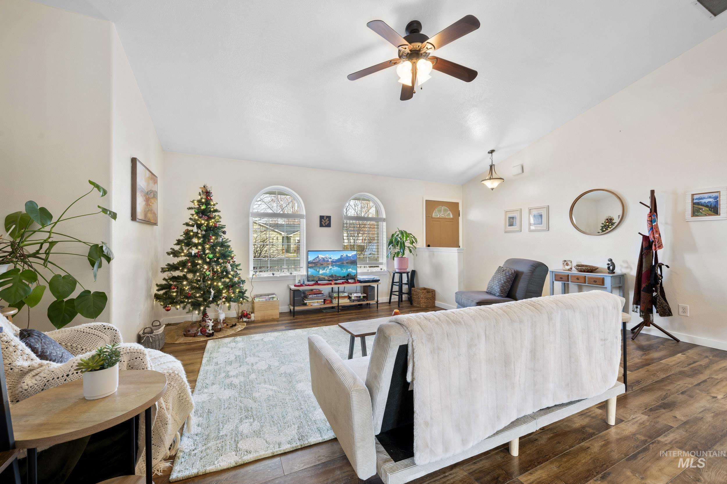 Living area featuring wood finished floors, vaulted ceiling, and ceiling fan