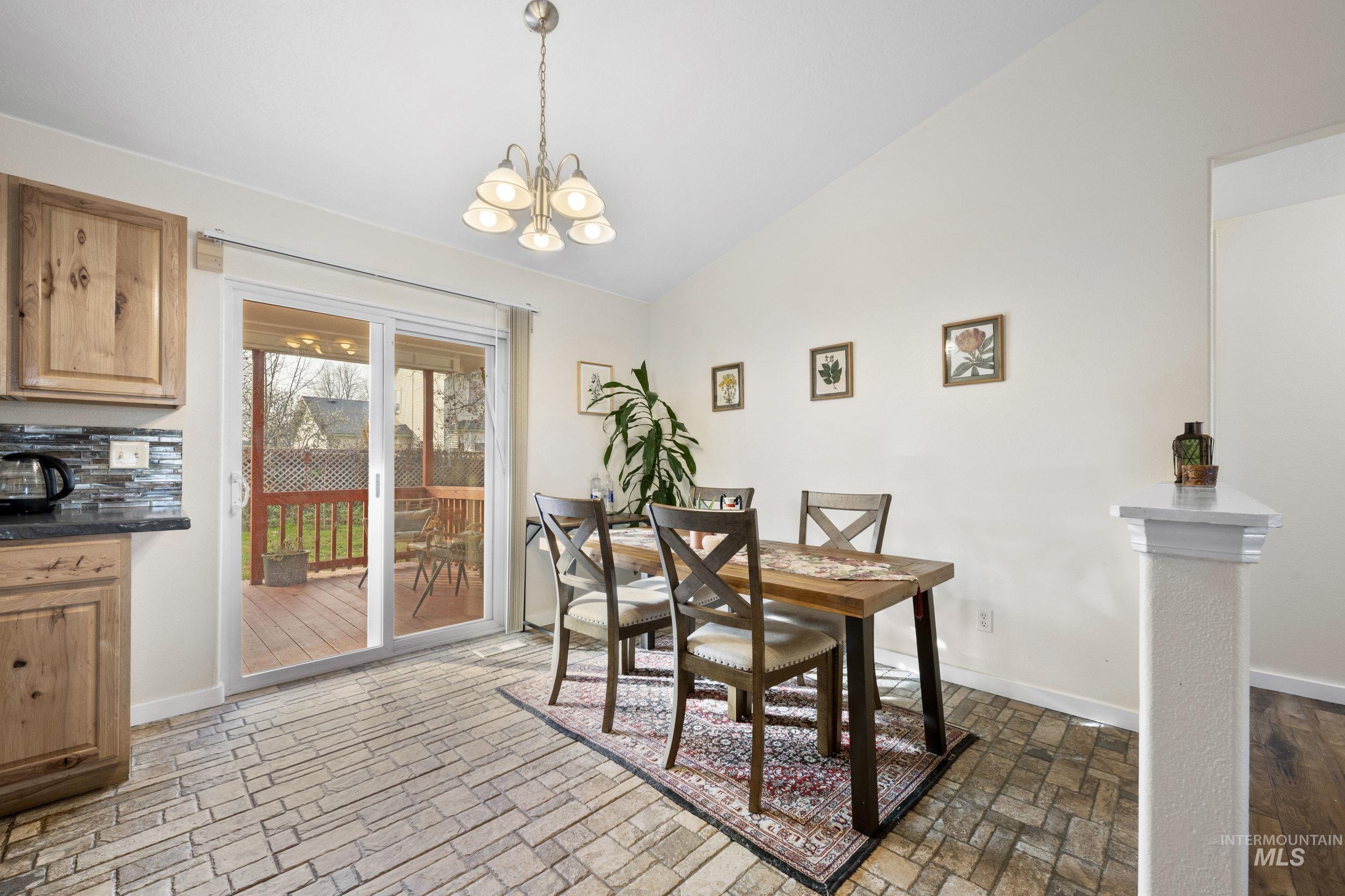 Dining area with lofted ceiling, a chandelier, and brick patterned flooring