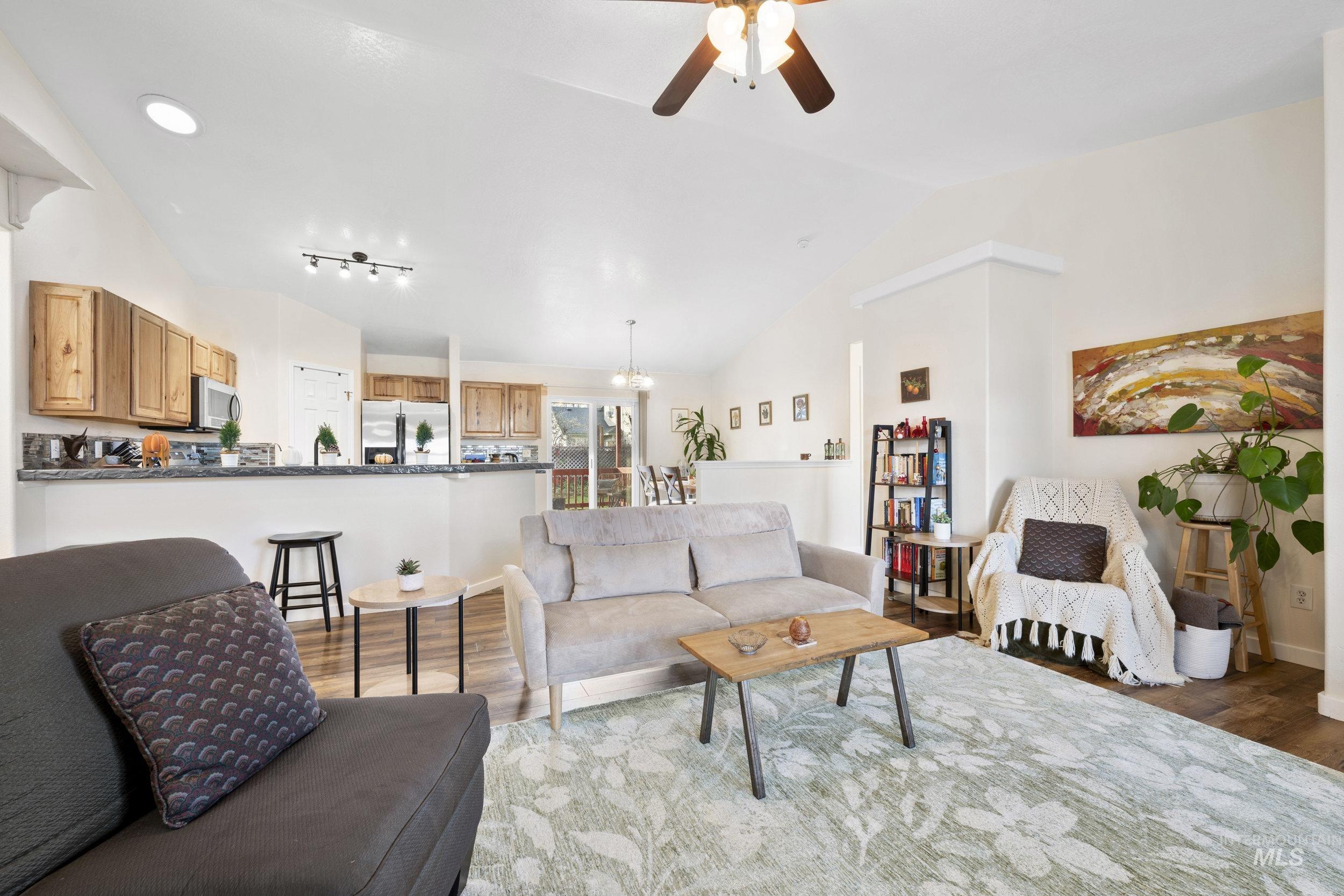 Living area featuring lofted ceiling, light wood-style floors, ceiling fan, and a chandelier