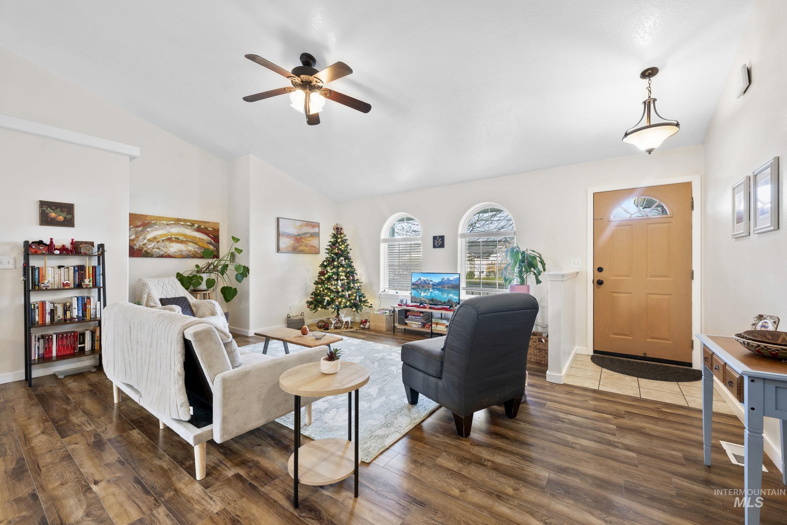 Living area featuring lofted ceiling, dark wood finished floors, and a ceiling fan