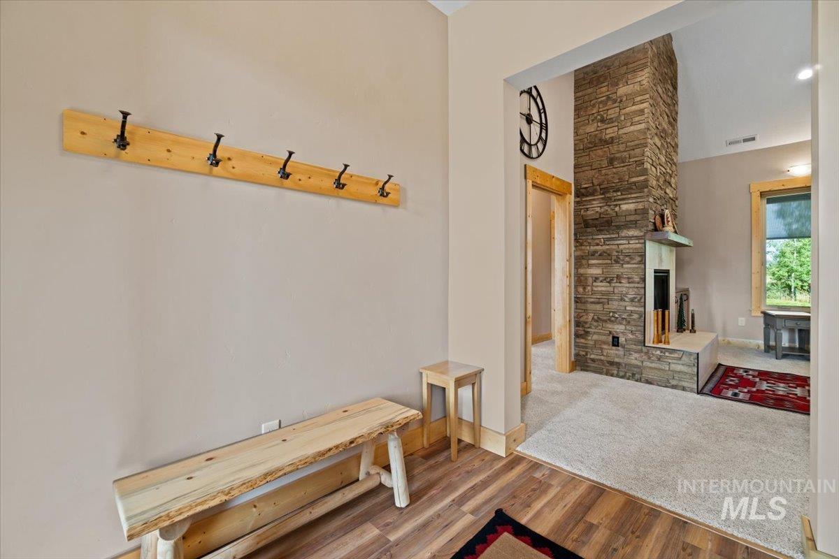 Mudroom featuring wood finished floors, a stone fireplace, and a high ceiling