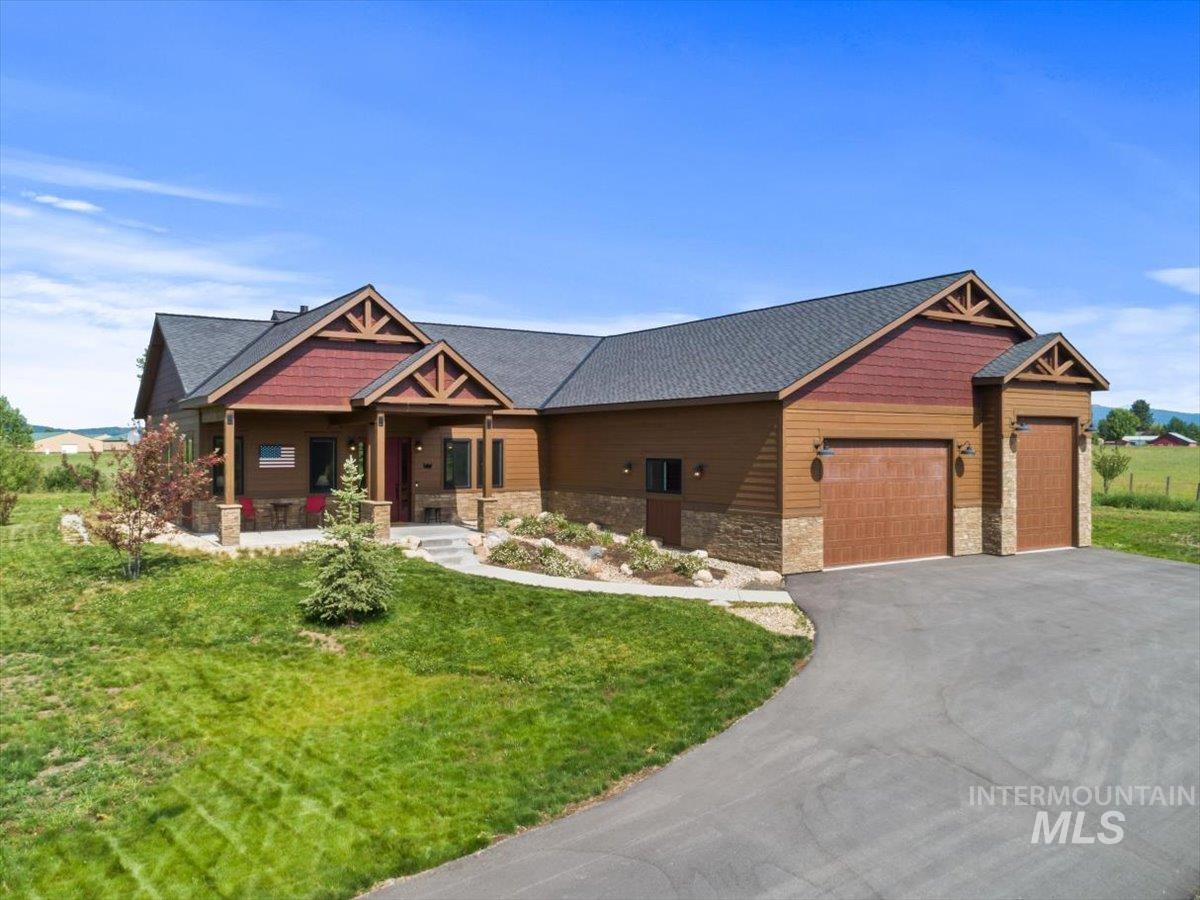Craftsman house featuring stone siding, a porch, asphalt driveway, a garage, and a front yard
