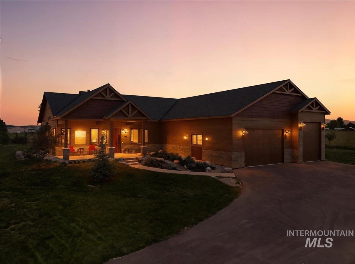 Craftsman house featuring a porch, a front lawn, a garage, driveway, and stone siding