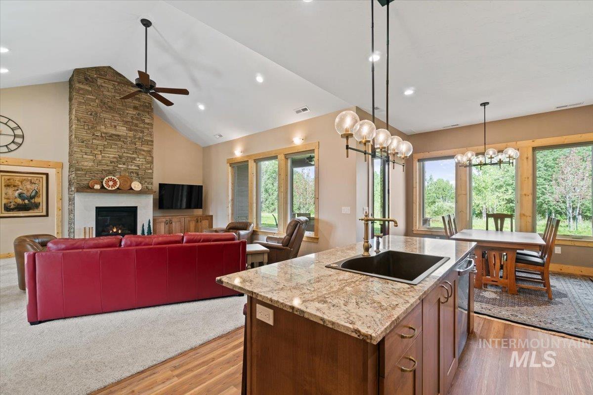 Kitchen with light wood-type flooring, ceiling fan, decorative light fixtures, a fireplace, and recessed lighting