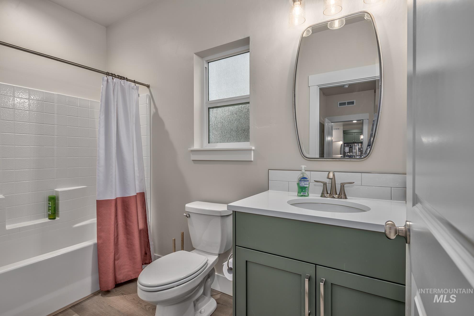 Bathroom featuring shower / bath combo with shower curtain, vanity, and wood finished floors