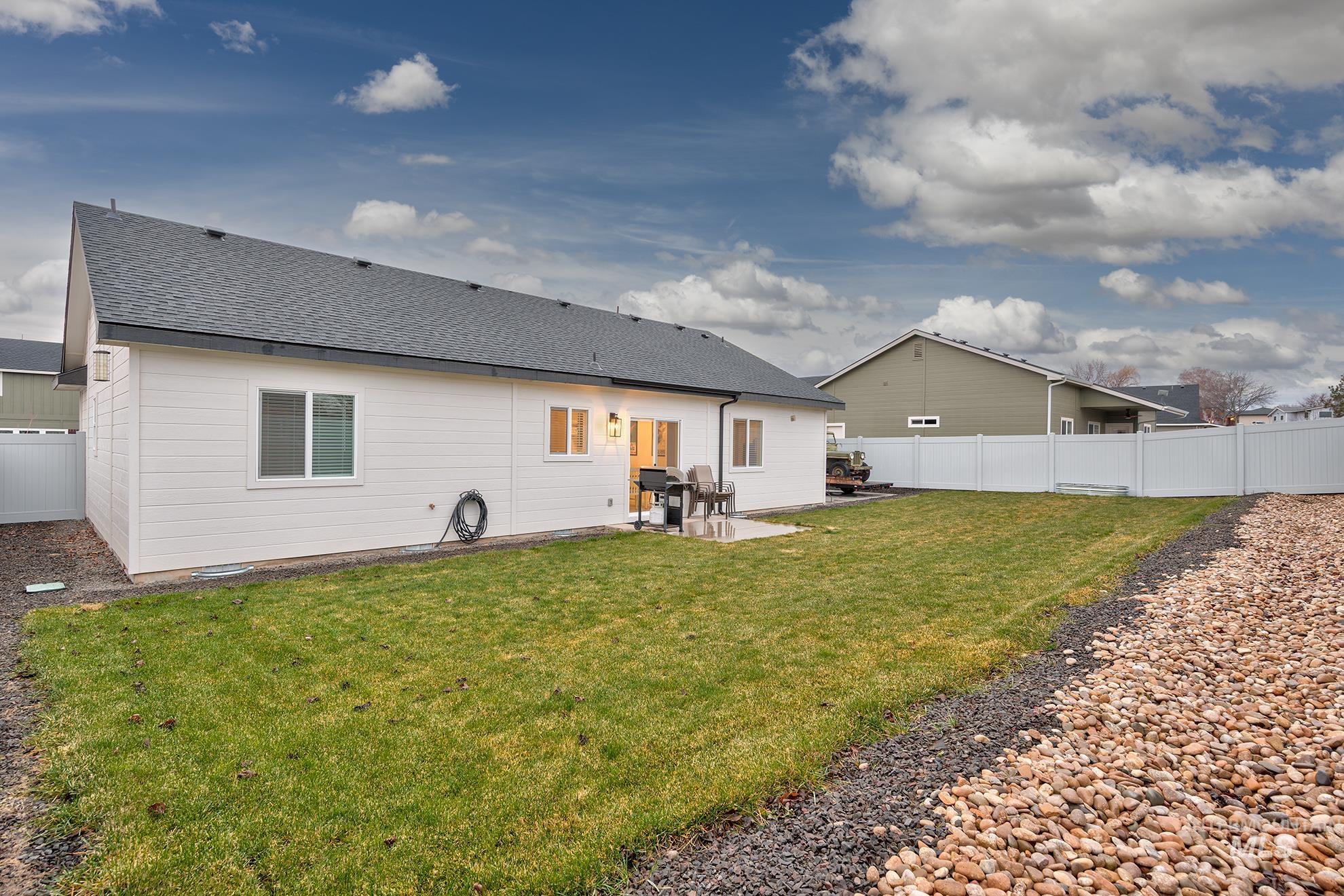 Rear view of property with a fenced backyard, a shingled roof, and a patio area