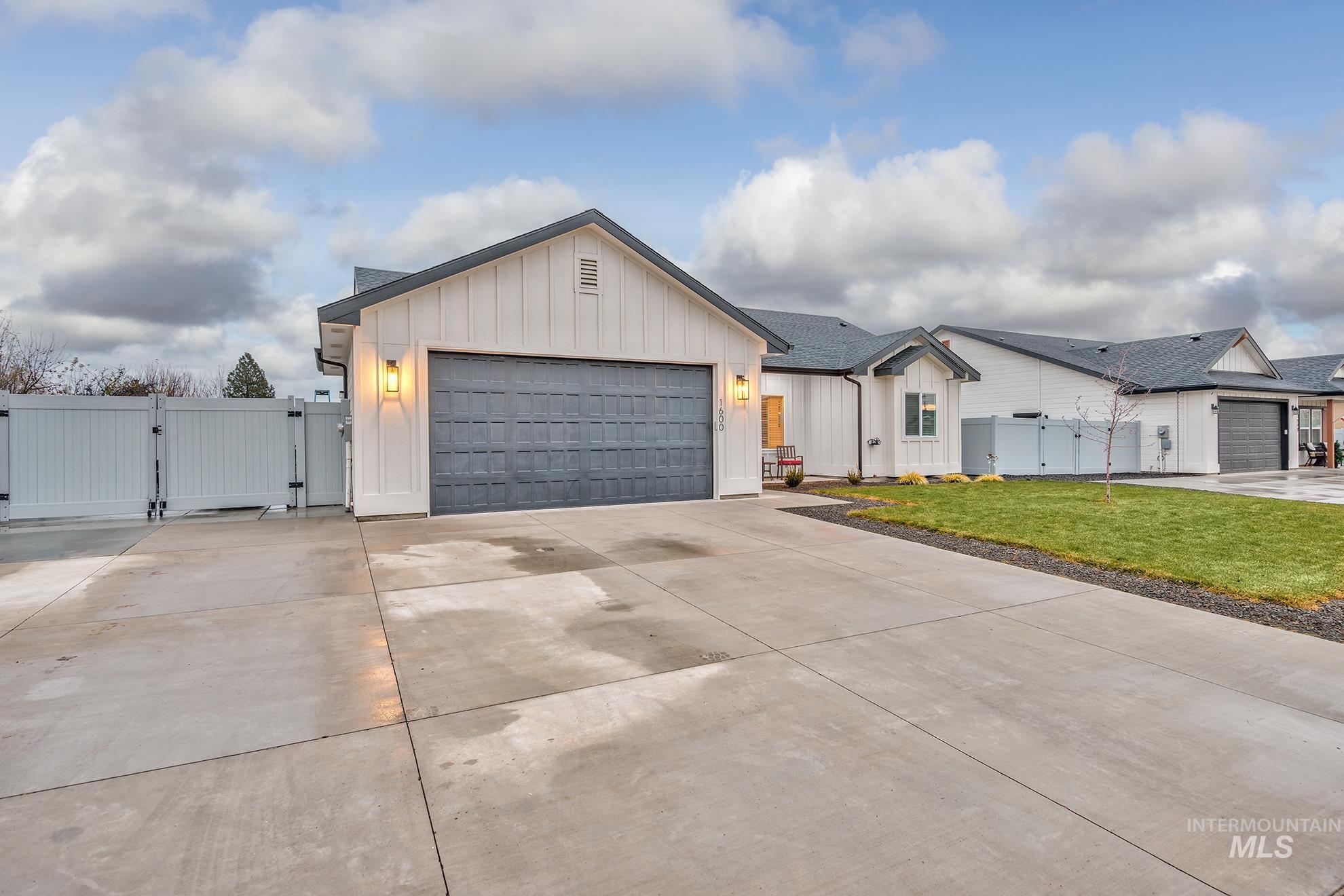 Modern farmhouse featuring a gate, board and batten siding, and driveway