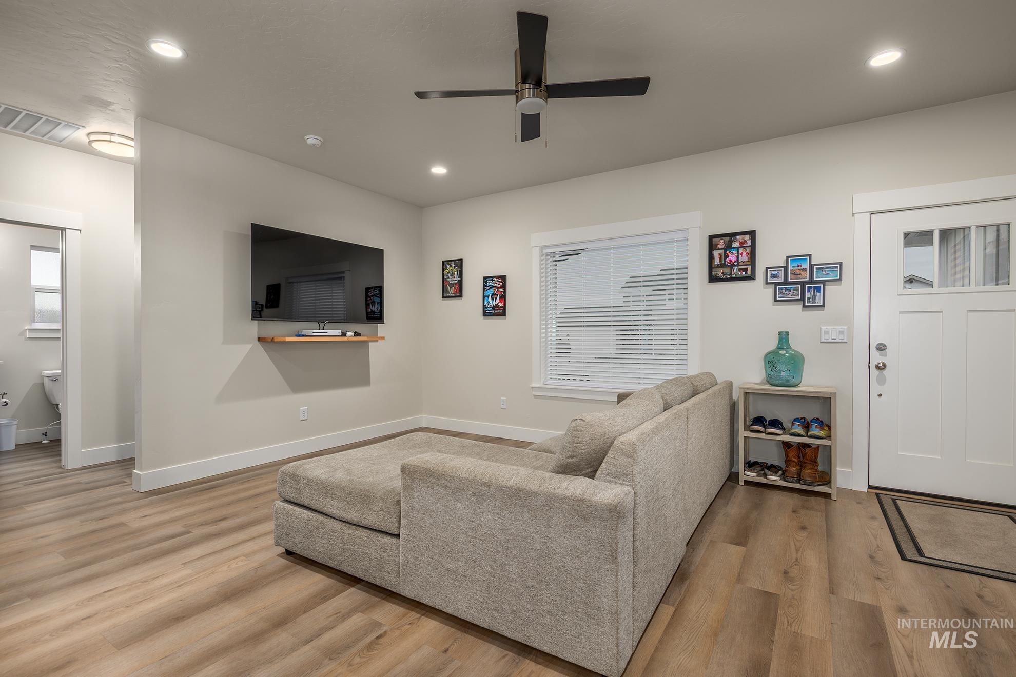 Living room featuring light wood-style floors, a ceiling fan, and recessed lighting