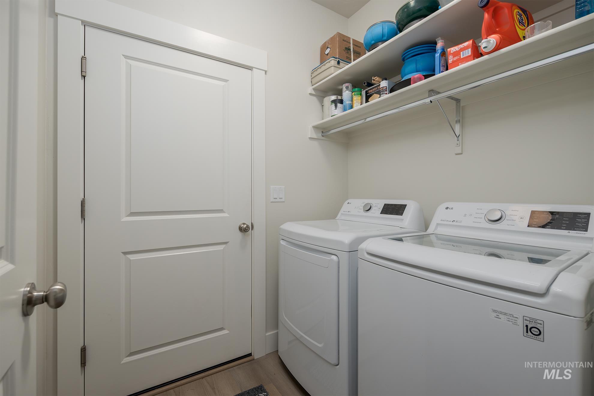 Laundry room with washing machine and clothes dryer and light wood finished floors