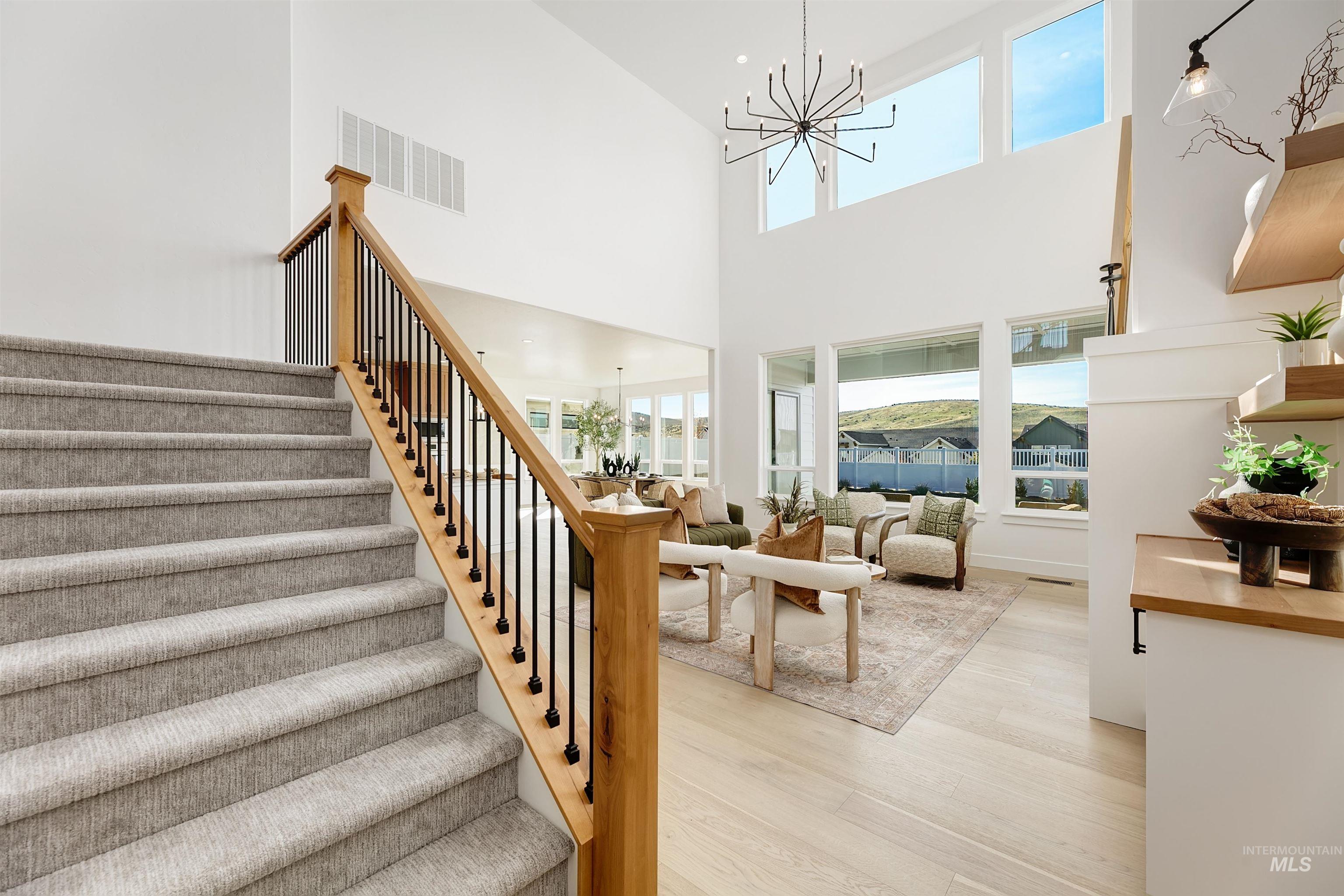 Stairway with suspended lighting, healthy amount of natural light, wood finished floors, and a high ceiling