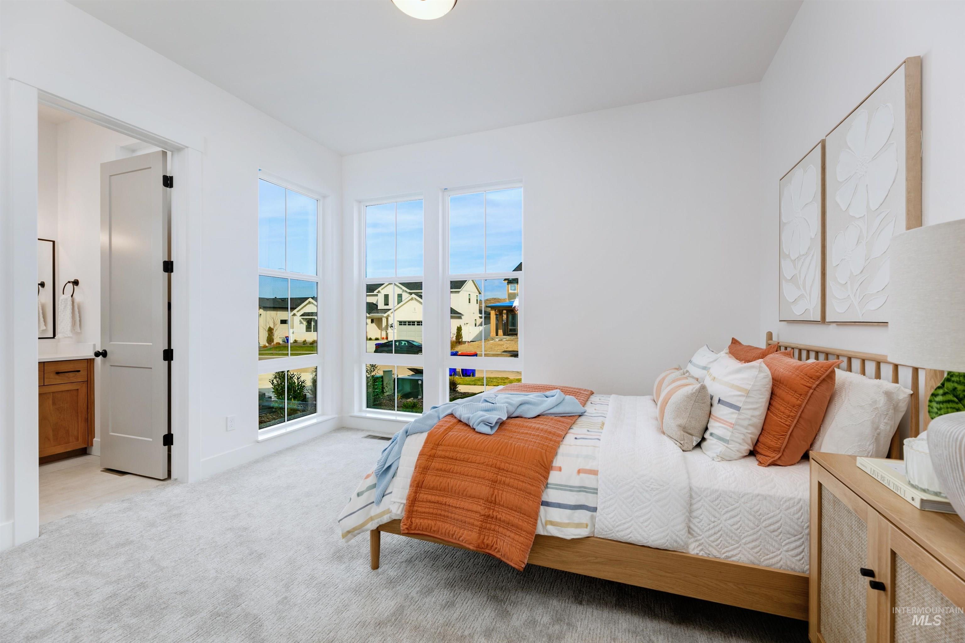 Bedroom with light colored carpet, ensuite bathroom, and a residential view