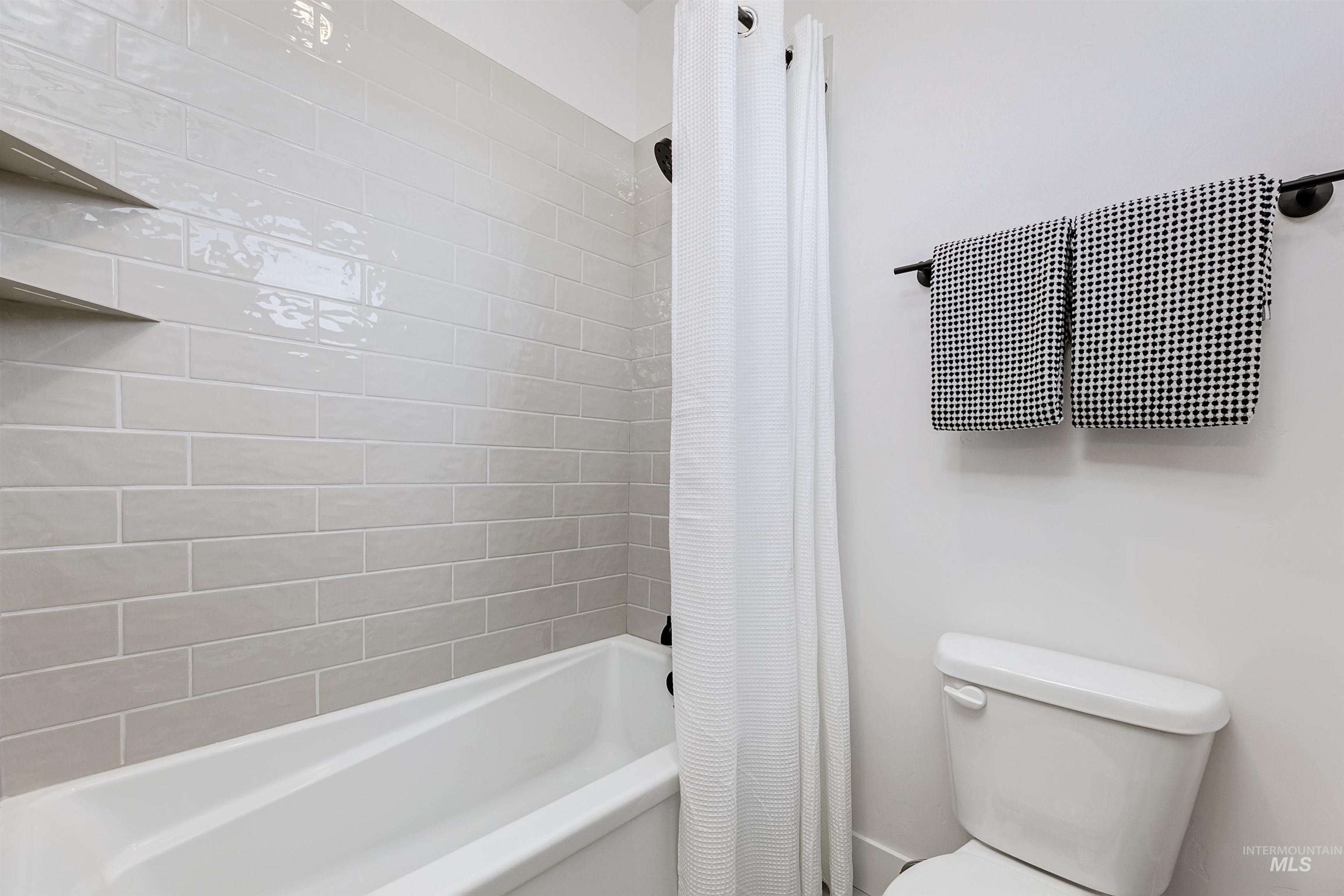 Bathroom featuring shower / bath combination with curtain and toilet