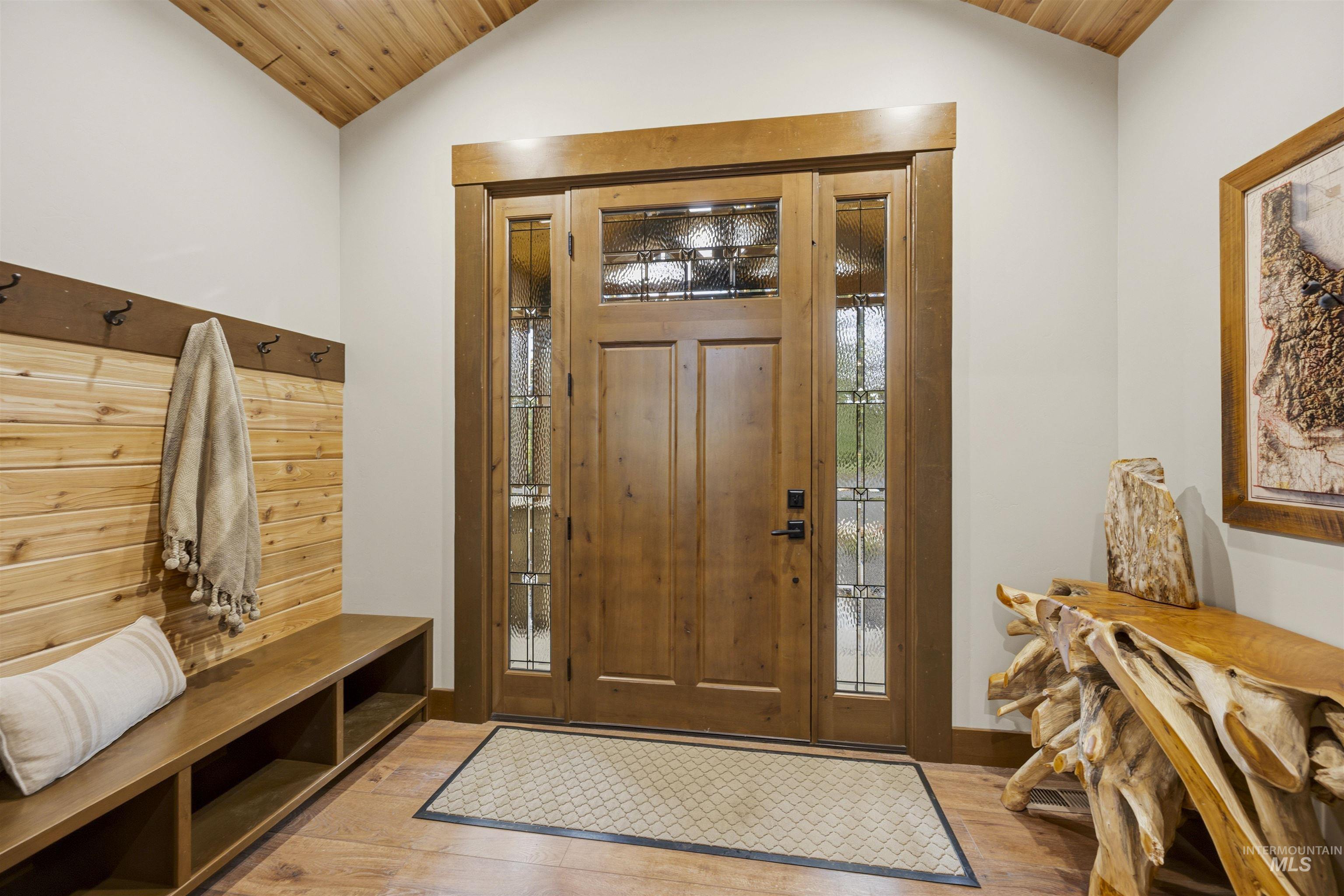 Entryway featuring a solid wood door with decorative glass sidelights, wood-finish flooring, a built-in bench with storage cubbies, and a built-in wall panel with hooks