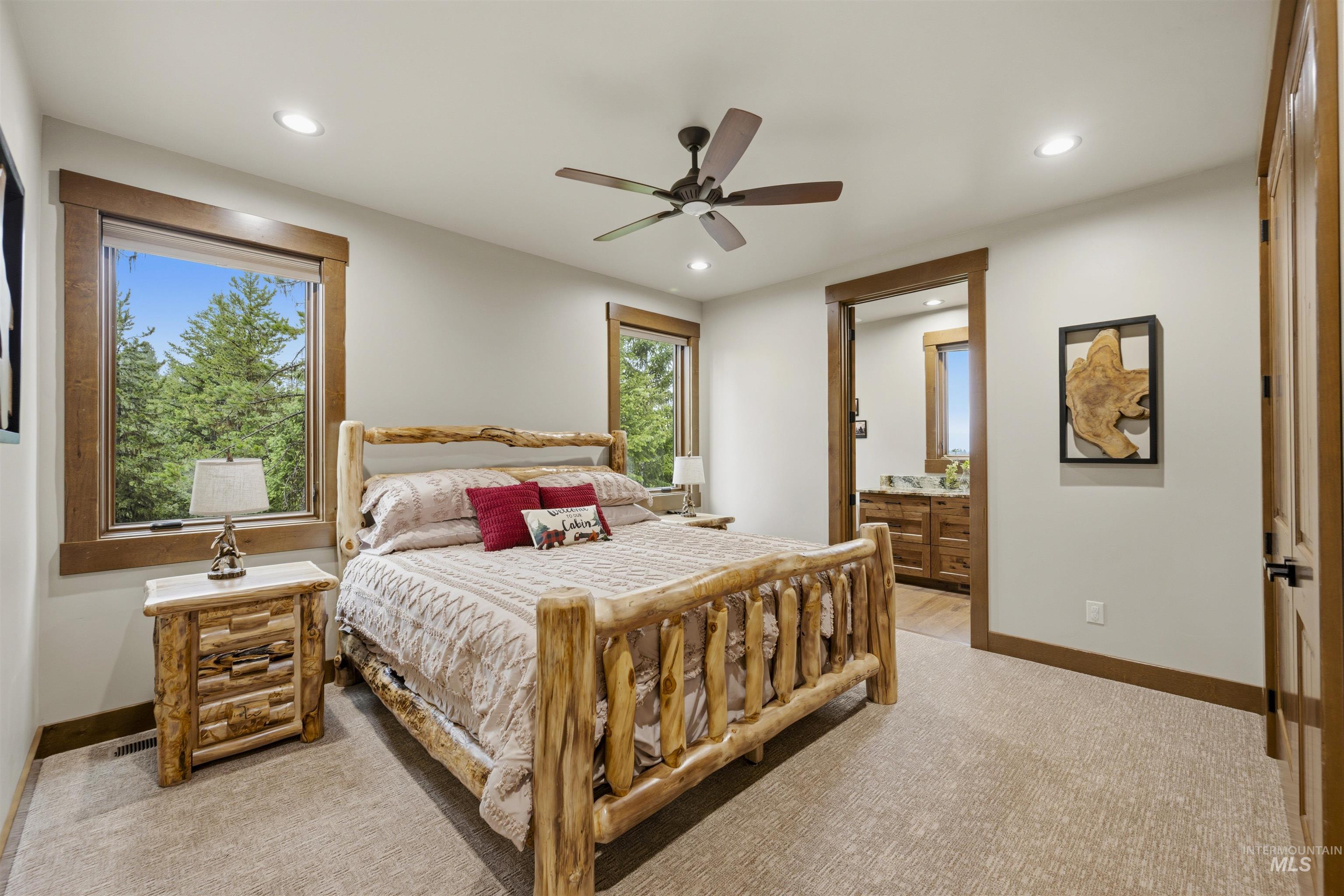 Recessed lighting illuminates the carpeted room, featuring wood-trimmed windows with natural surroundings Second Bedroom Main Level