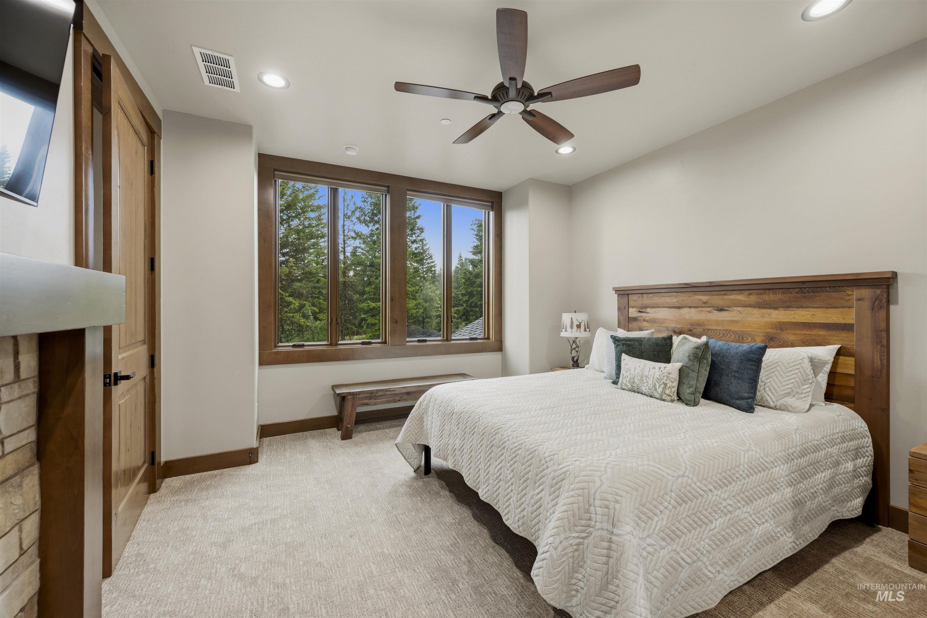 Bedroom featuring a wood-finish ceiling fan, recessed lighting, and a stone-clad fireplace with a mantle - Bedroom 5, Second Level