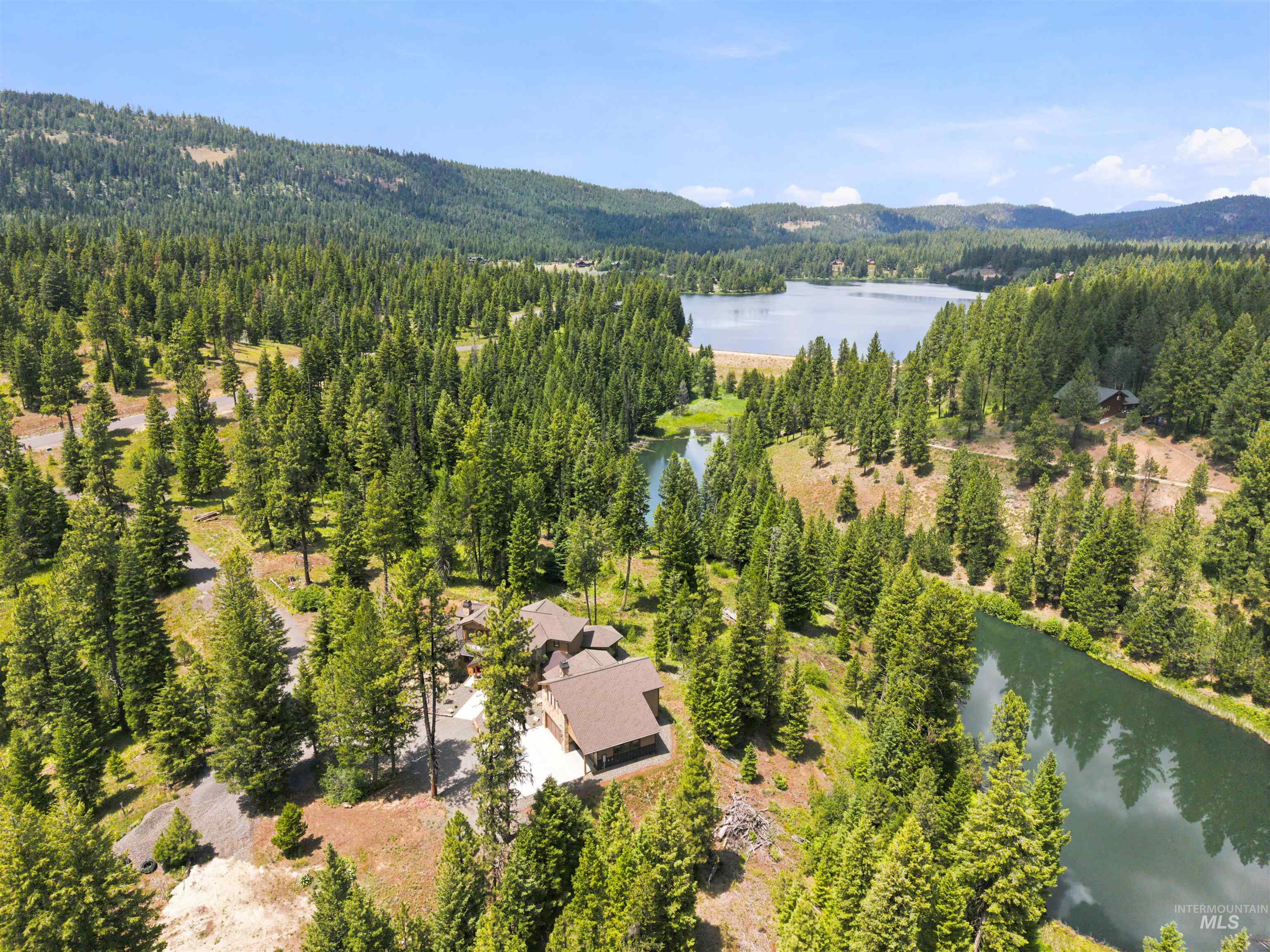 Expansive aerial capturing a brown-roofed residence nestled amongst dense evergreen trees